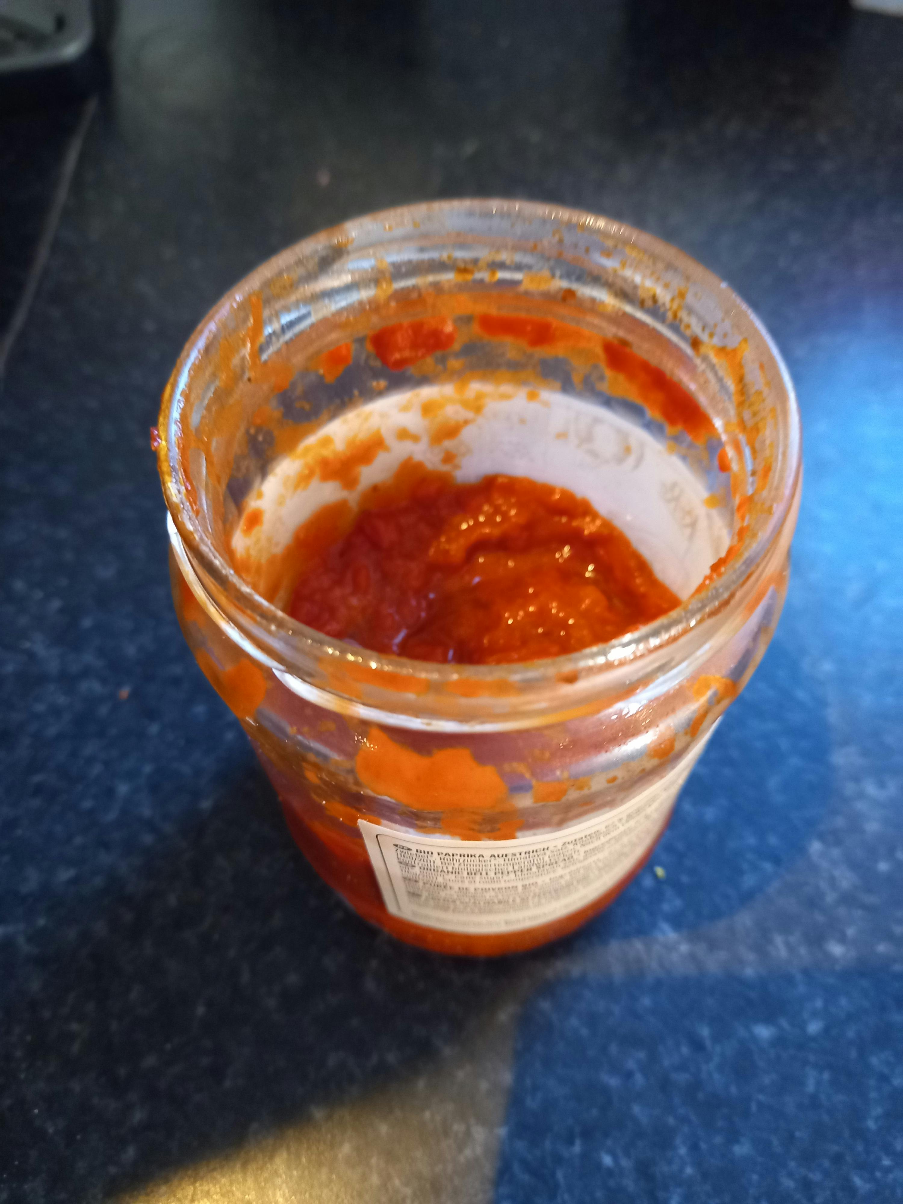 un bocal en verre rempli de sauce sur une table noire