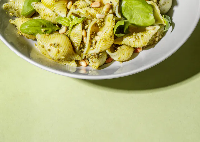 eine weiße Schüssel mit Nudeln mit pesto und Pinienkernen