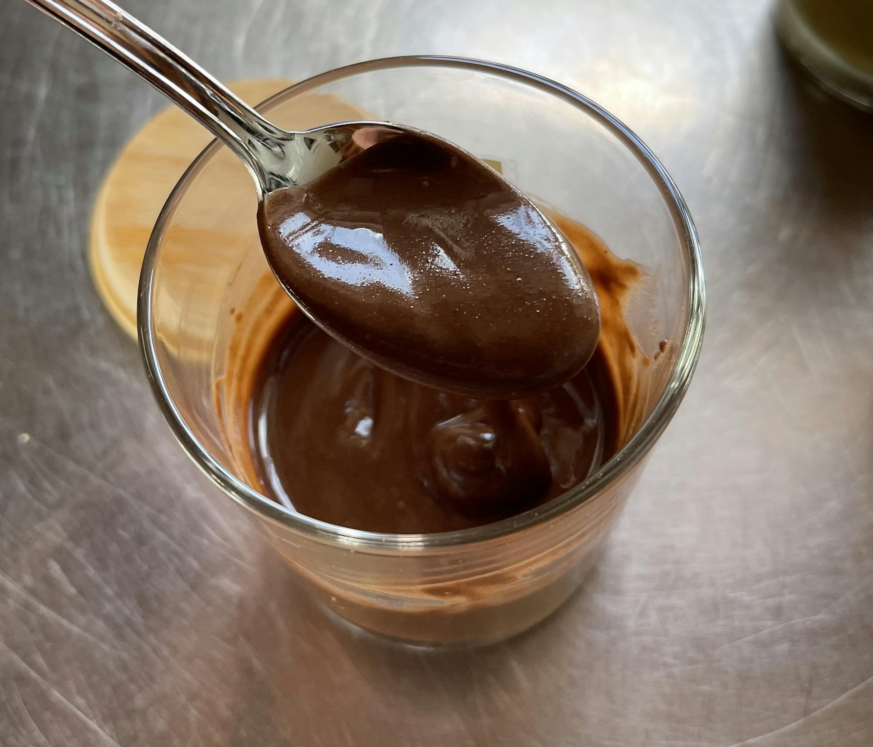 a spoon in a glass of chocolate pudding