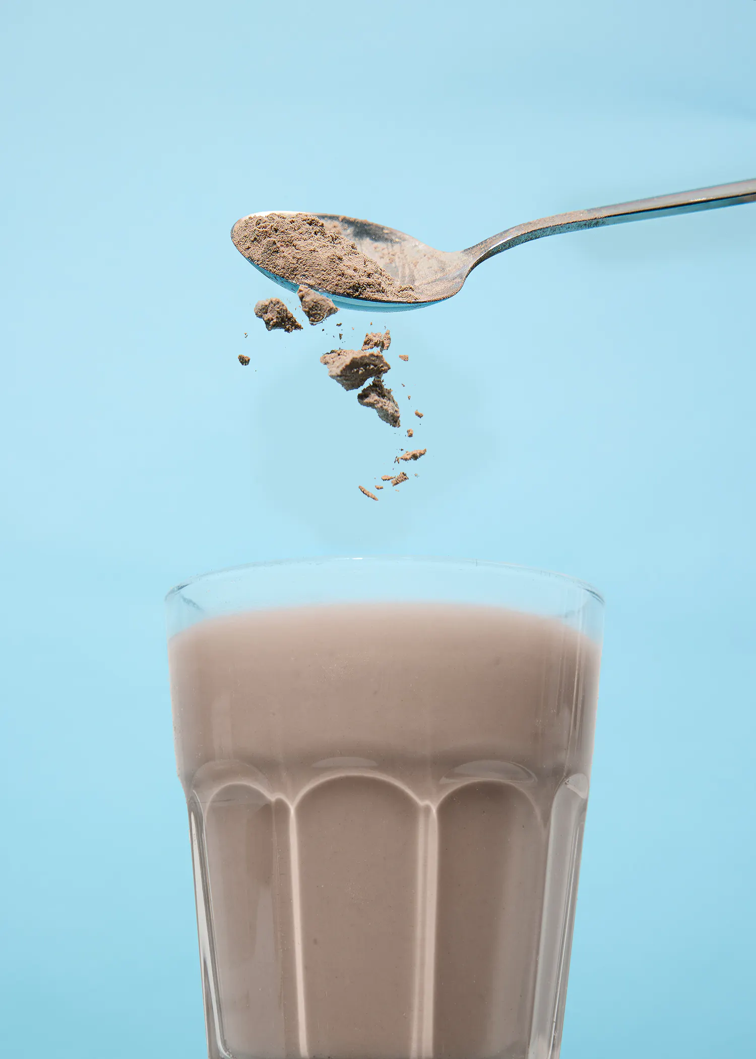 une cuillère est versée dans un verre de lait au chocolat