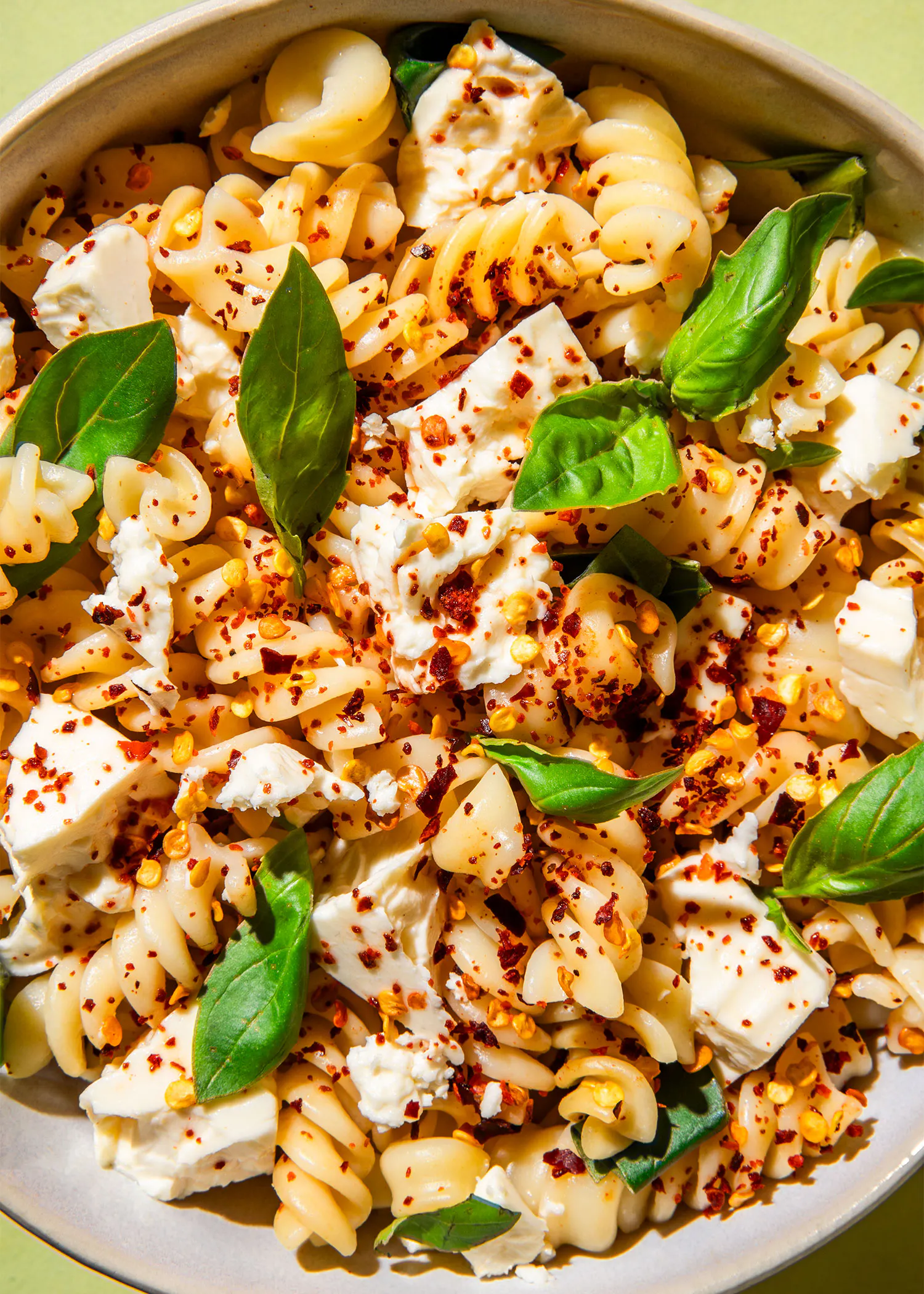 un plato de pasta con queso feta y albahaca