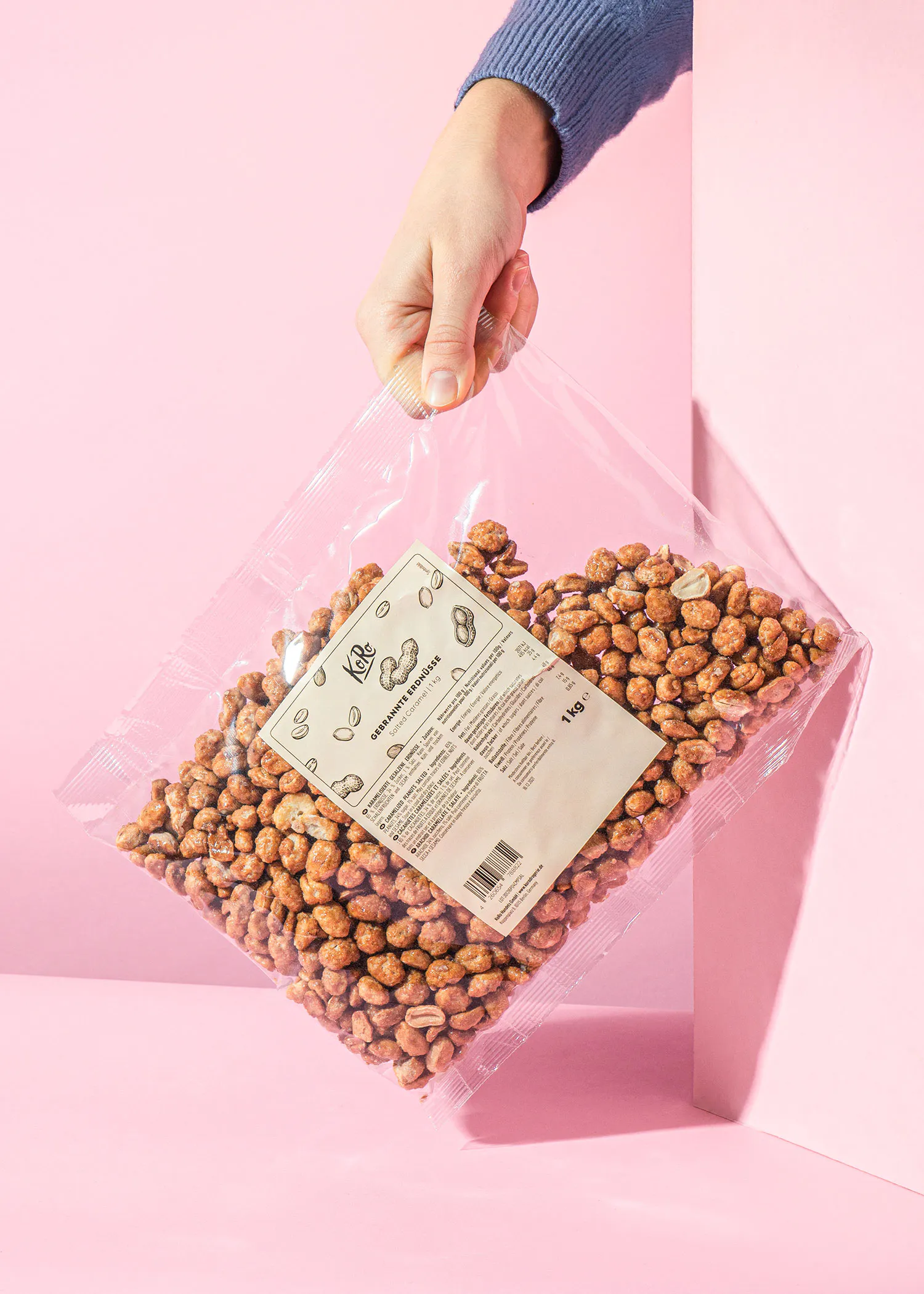 Gebrannte Erdnüsse in einer Verpackung, am oberen Ende festgehalten von einer Hand