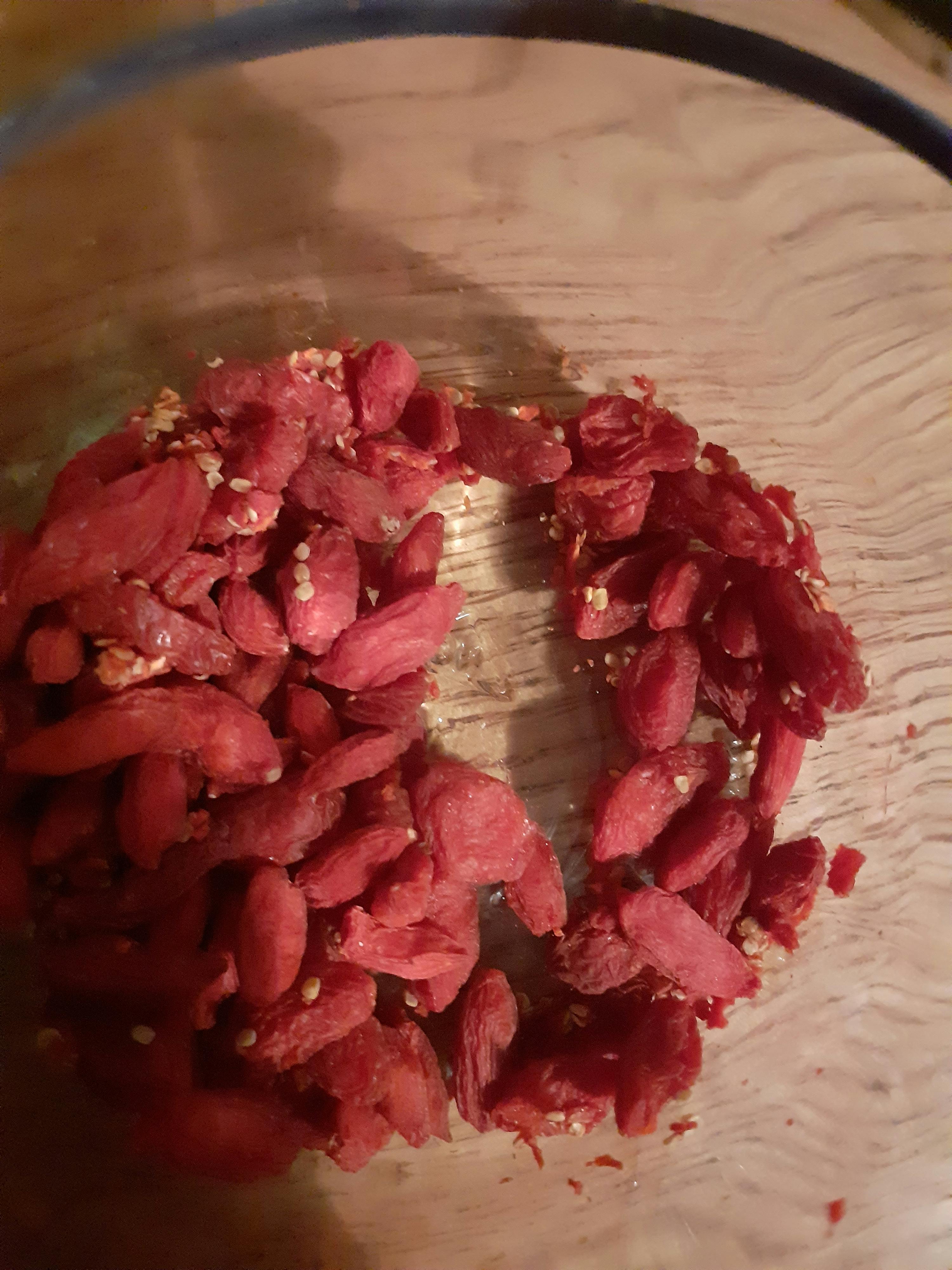 a glass bowl filled with red berries on a wooden table