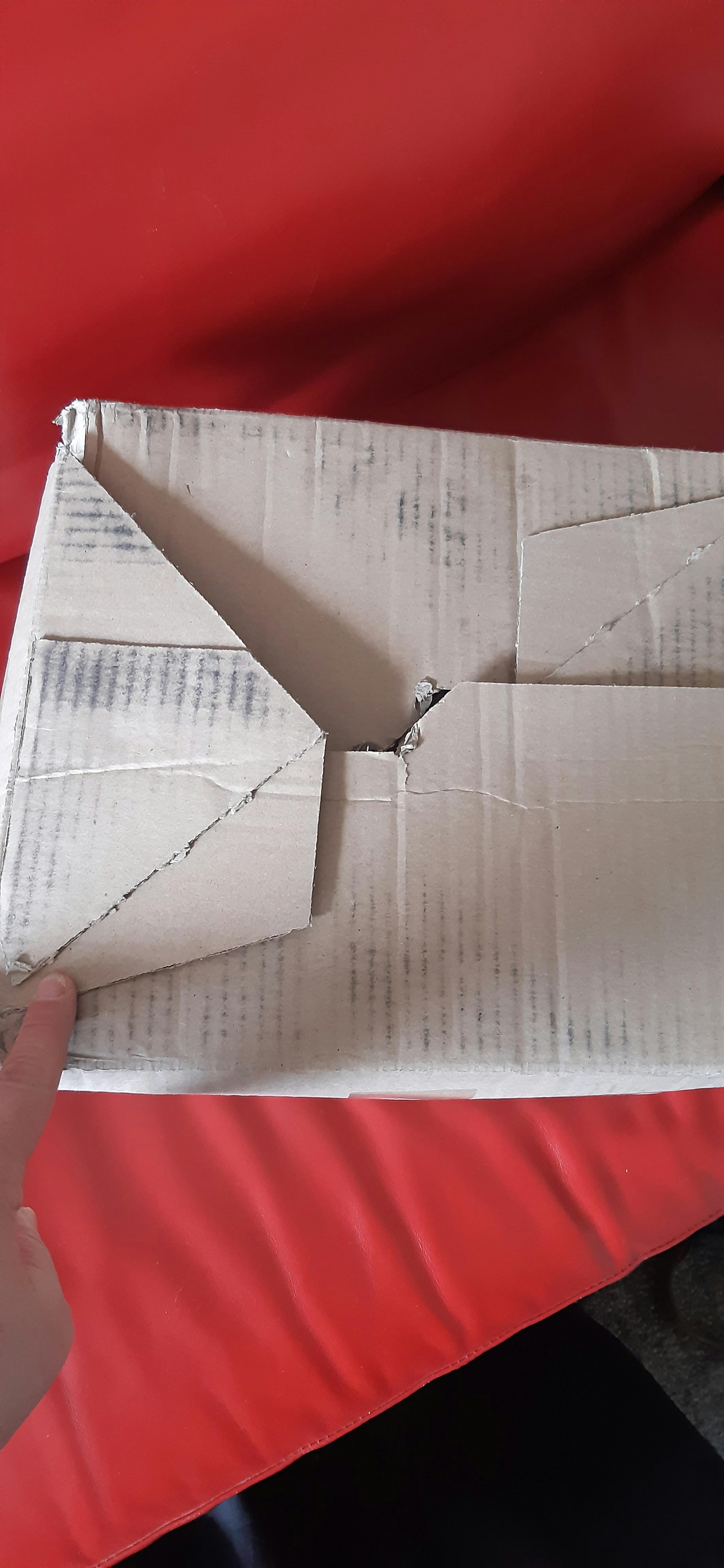 a person is holding a cardboard box that has a hole in it