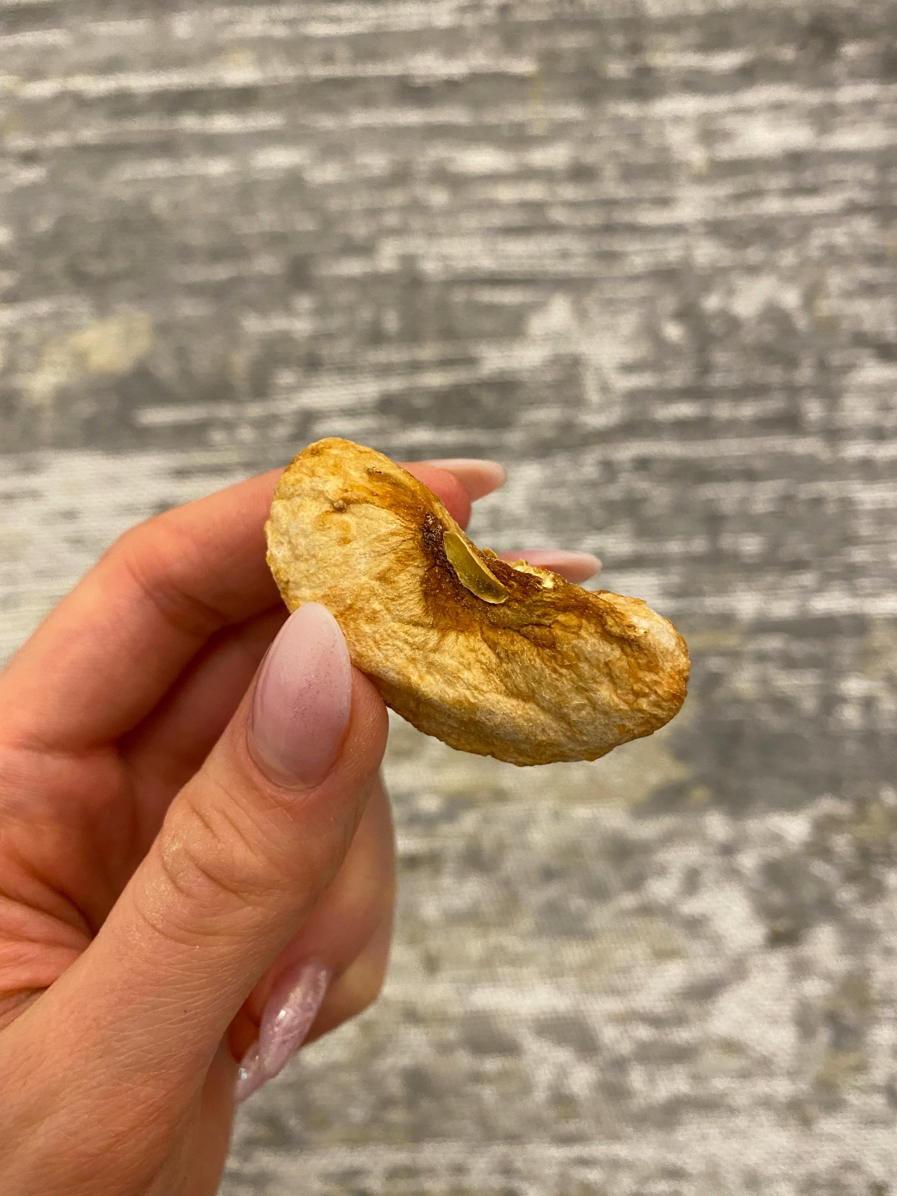 a woman holds a piece of dried apple in her hand
