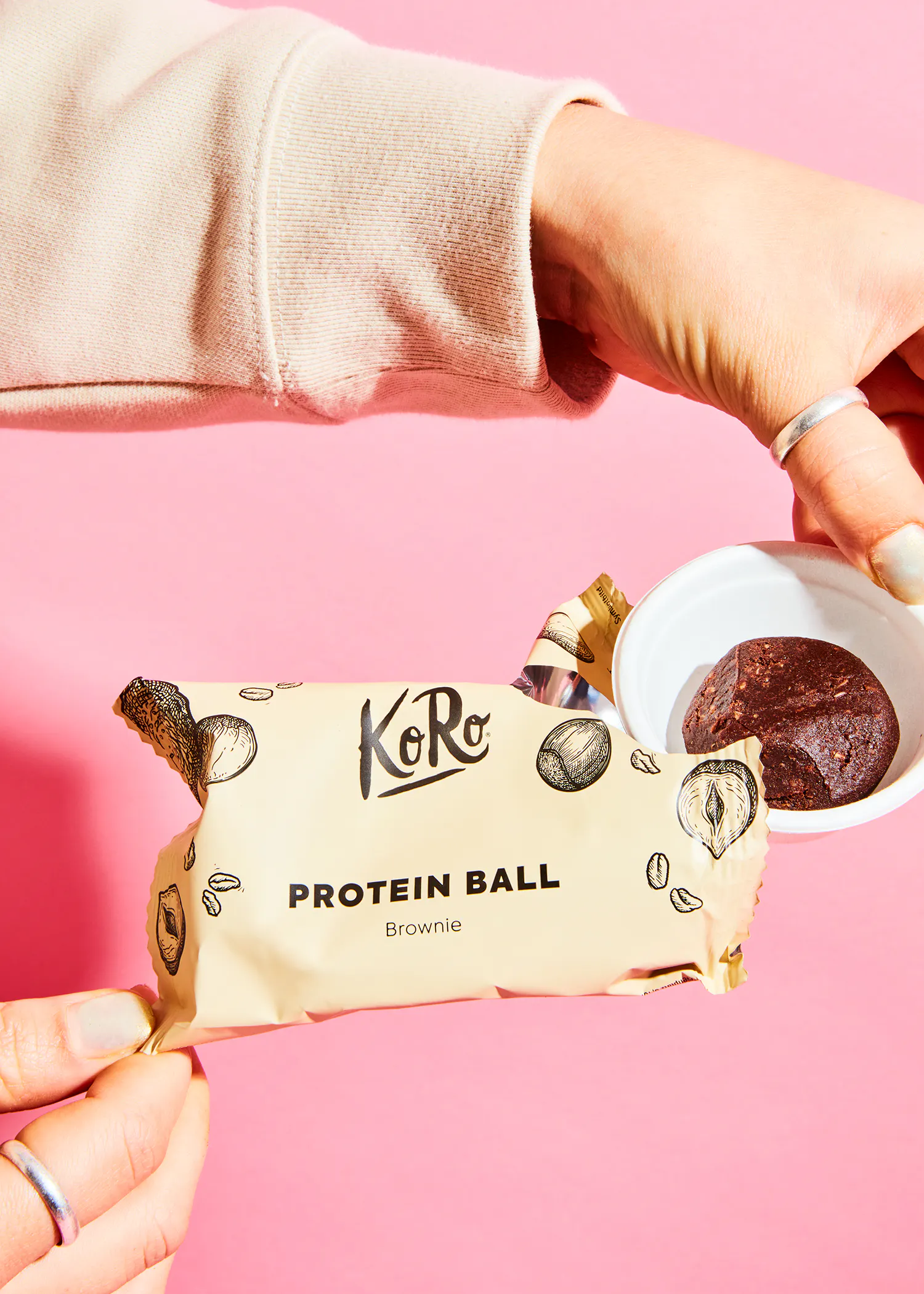 a person holding a package of koro protein ball brownie