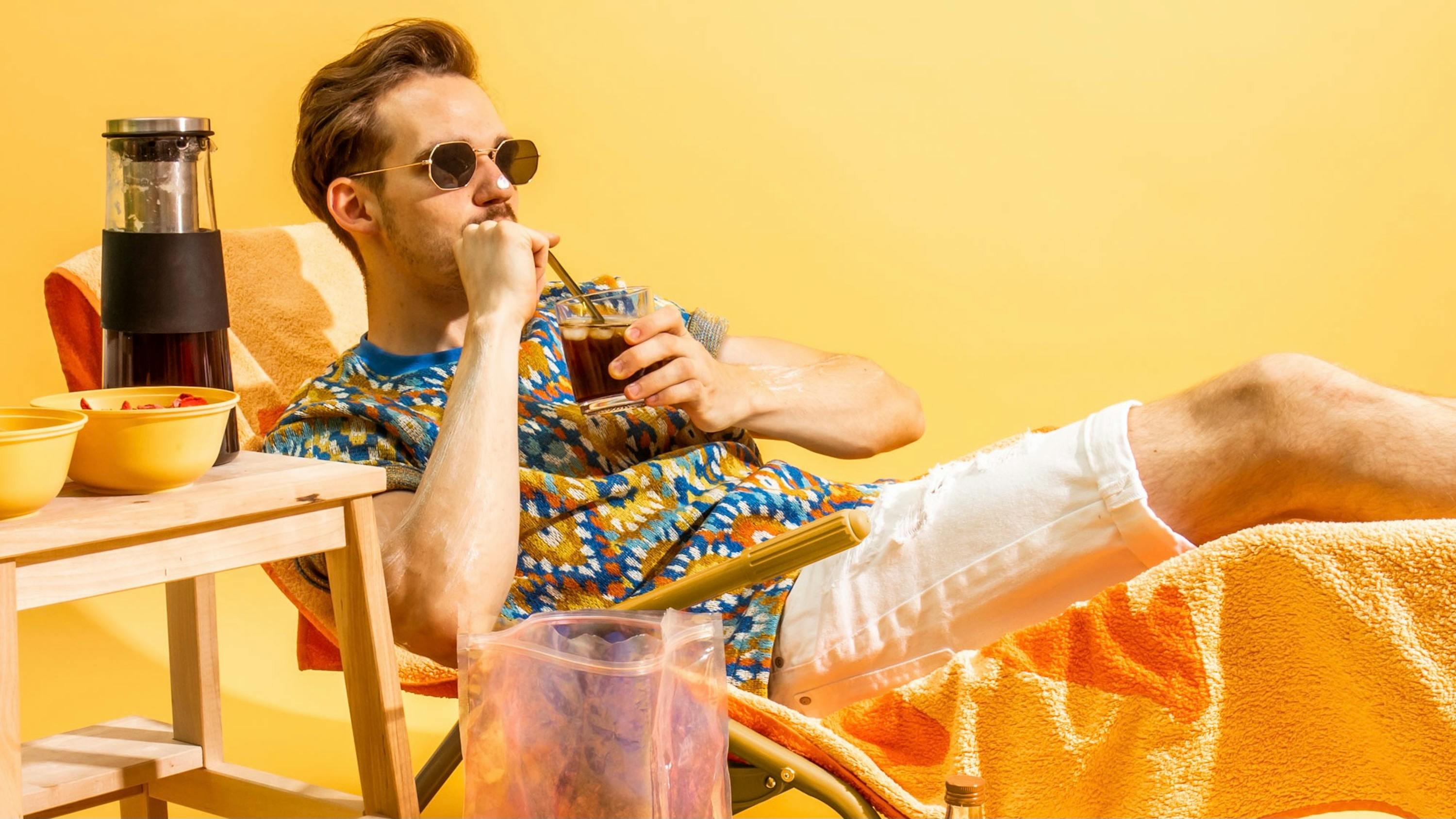 a man sitting in a chair drinking a drink through a straw