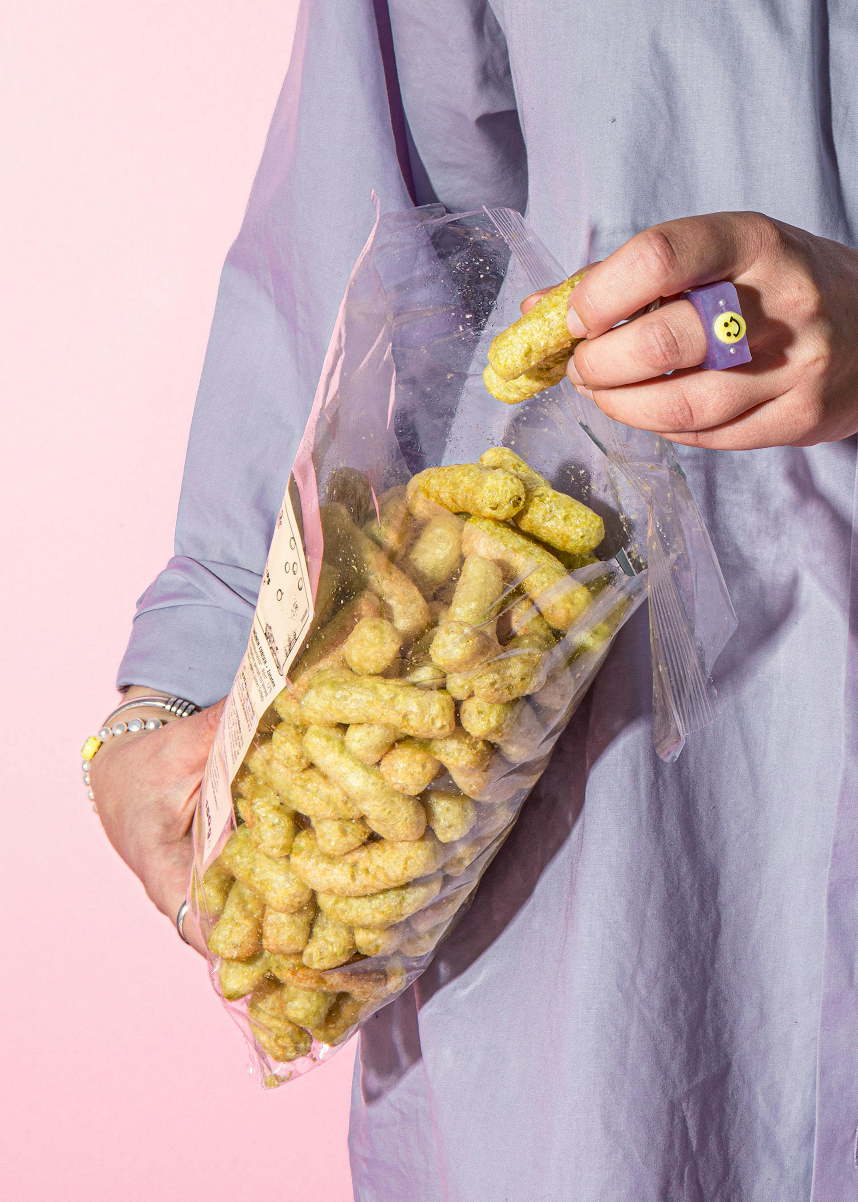 una persona con un anello viola tiene in mano un sacchetto di crackers