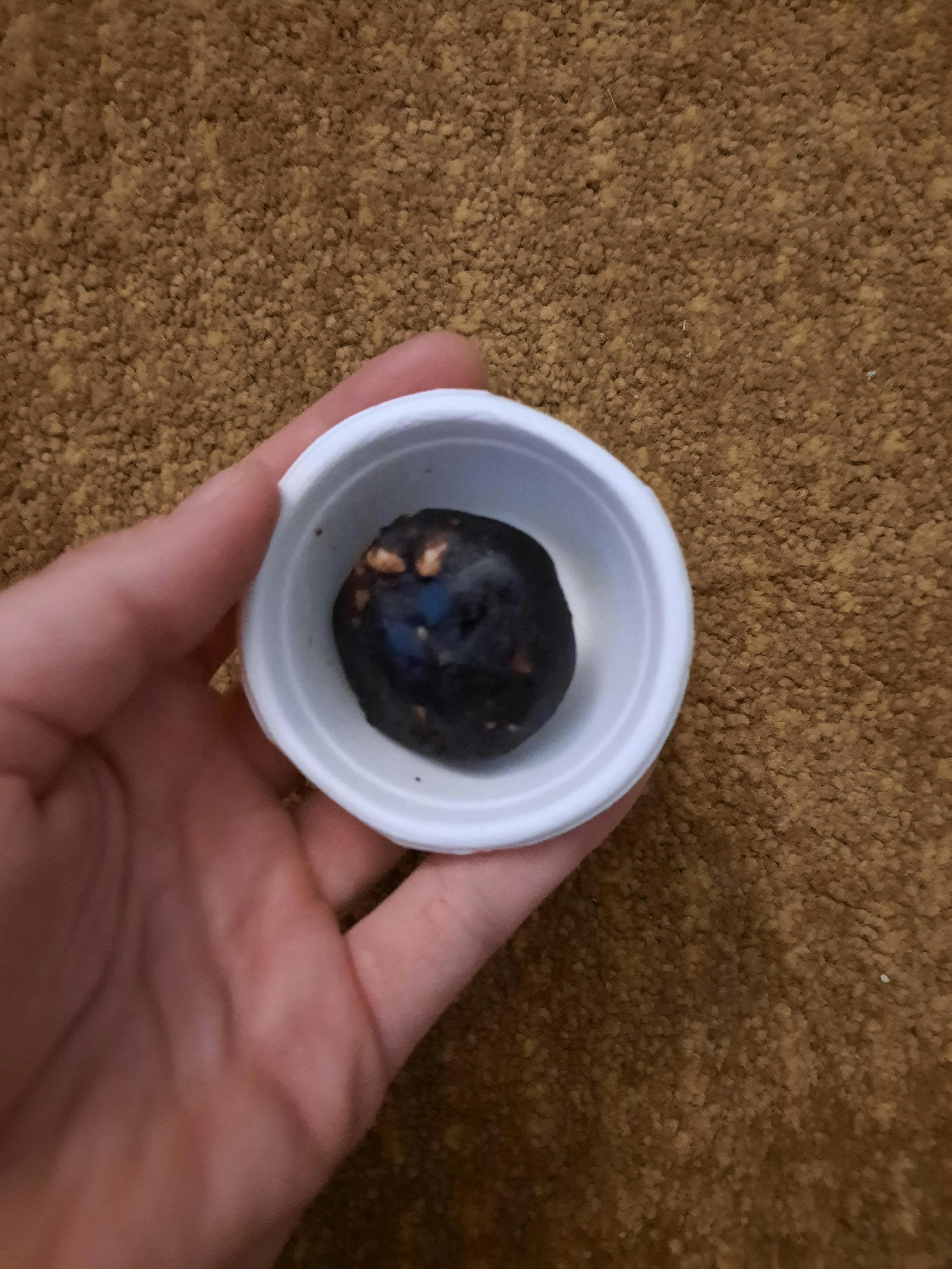 une personne tient une petite tasse blanche avec une boule noire dedans