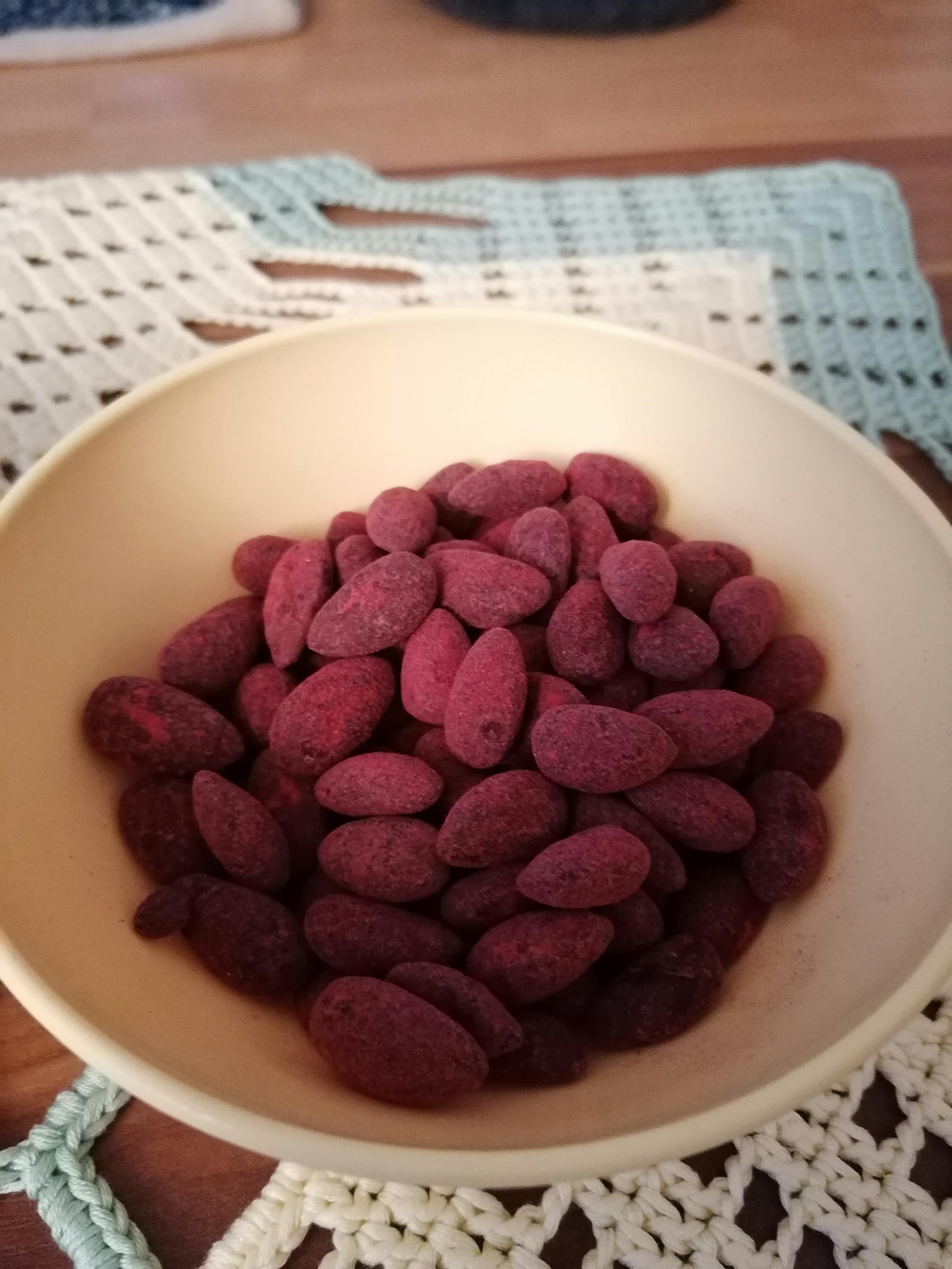 eine weiße Schüssel mit roten Mandeln auf einem Tisch