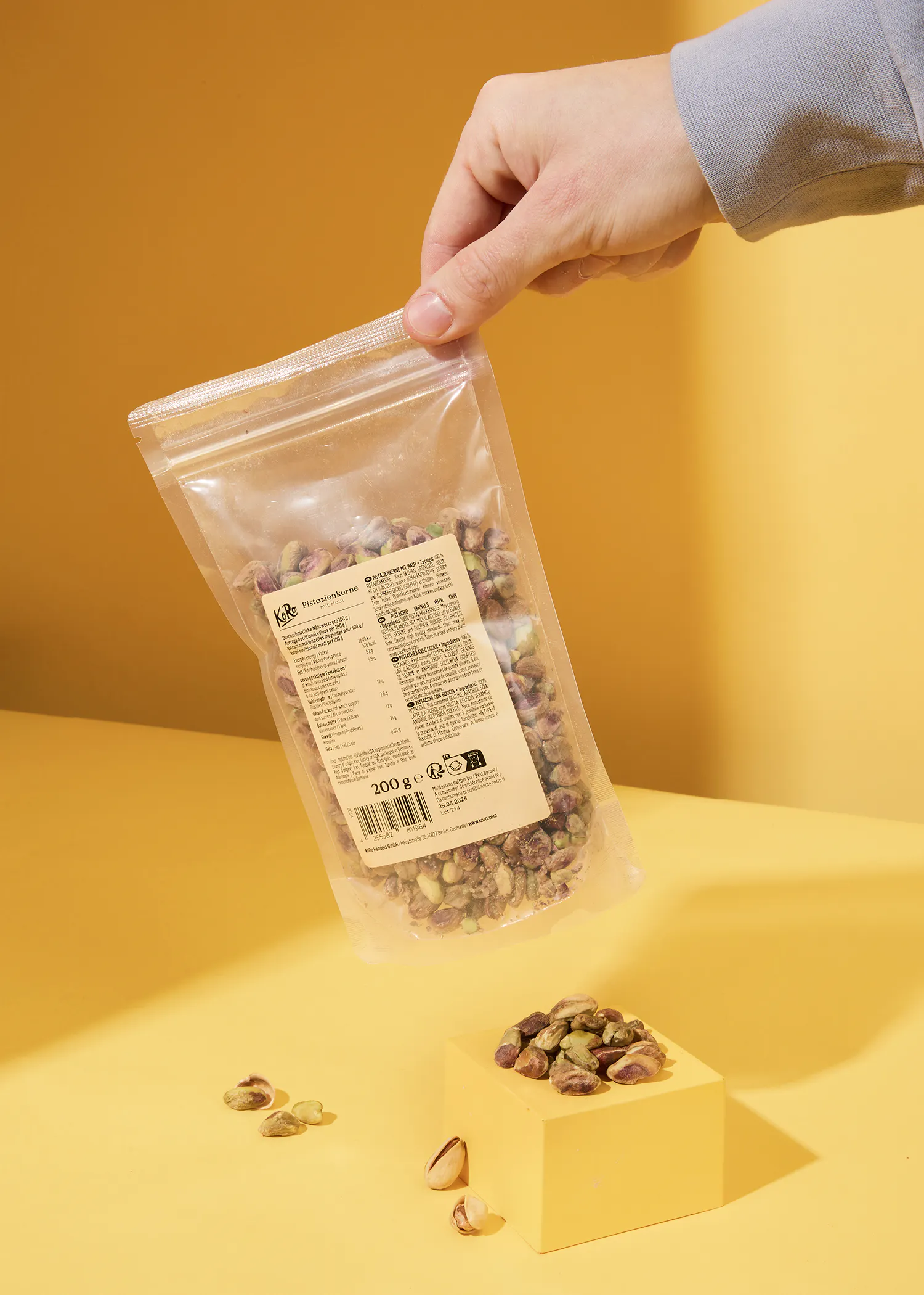 a person is holding a bag of pistachios on a yellow table