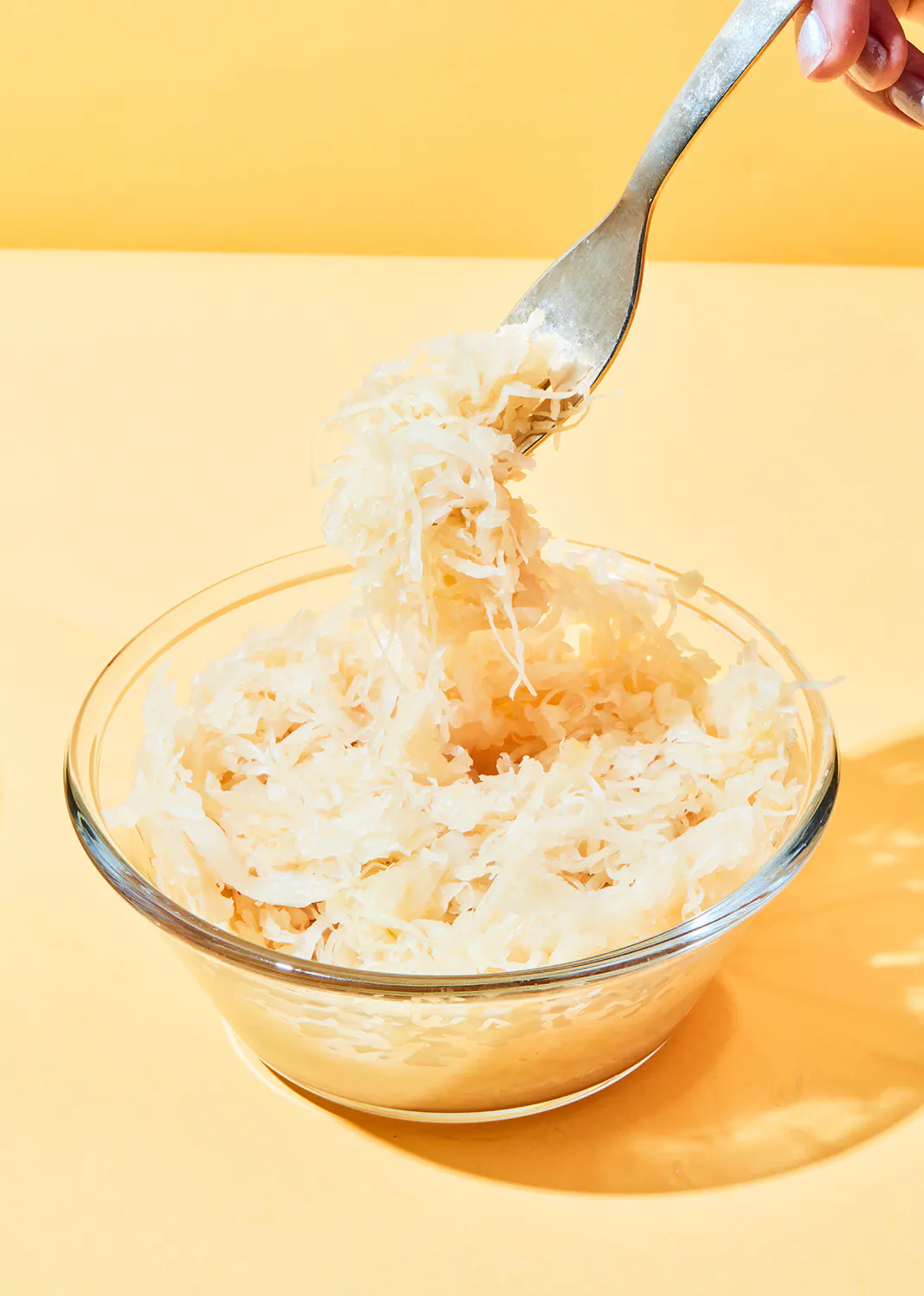 une personne tient une fourchette au-dessus d' un bol de sauerkraut