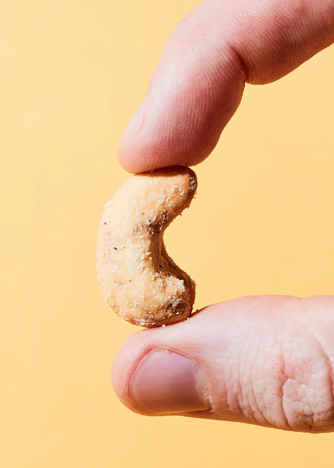 une personne tient un noix de cajou sur son doigt