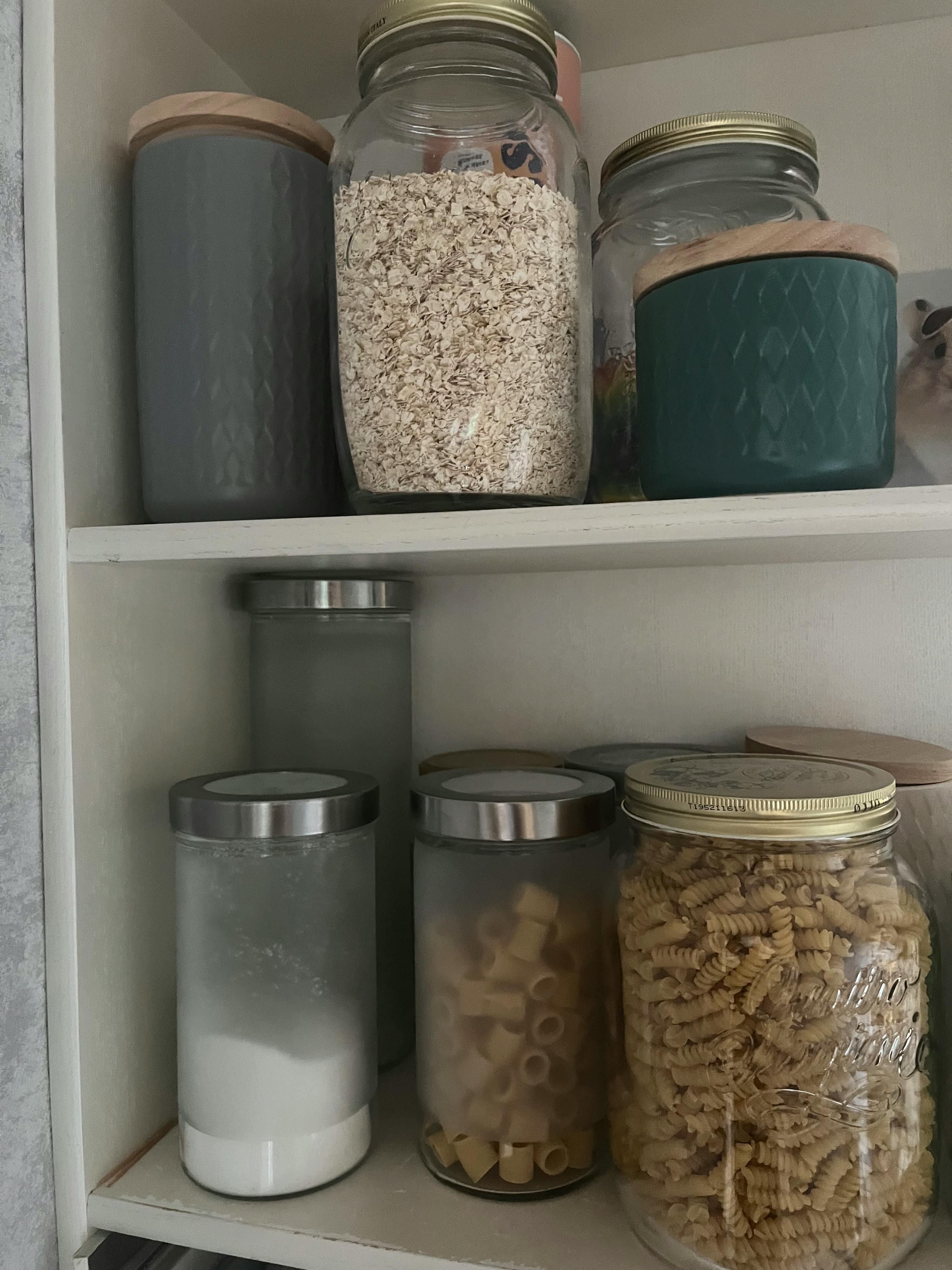 des bocaux remplis de pâtes et d' avoine se trouvent sur une étagère