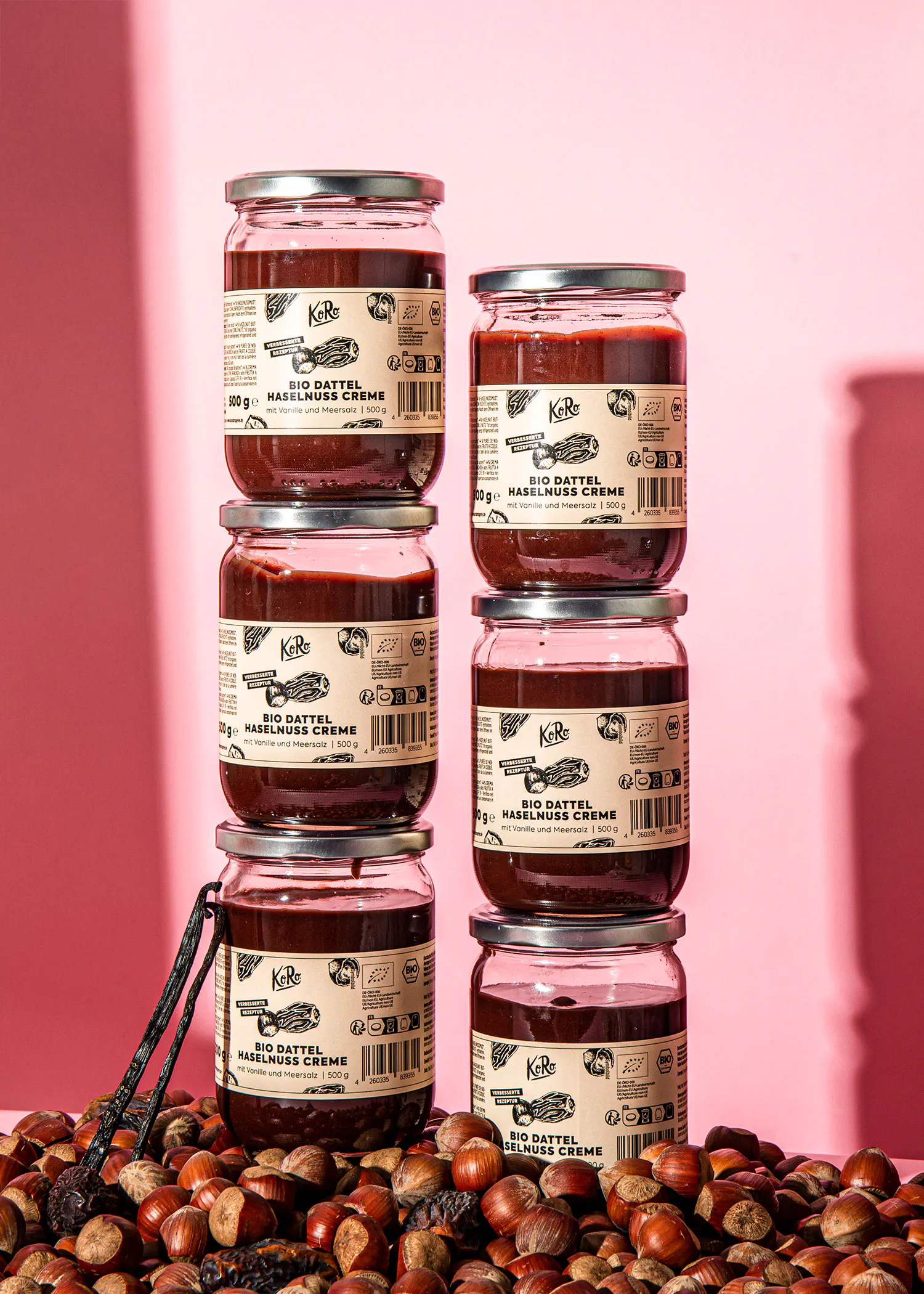 sechs Gläser bio dattel-haselnuss-creme stehen neben einem Haufen Haselnüsse