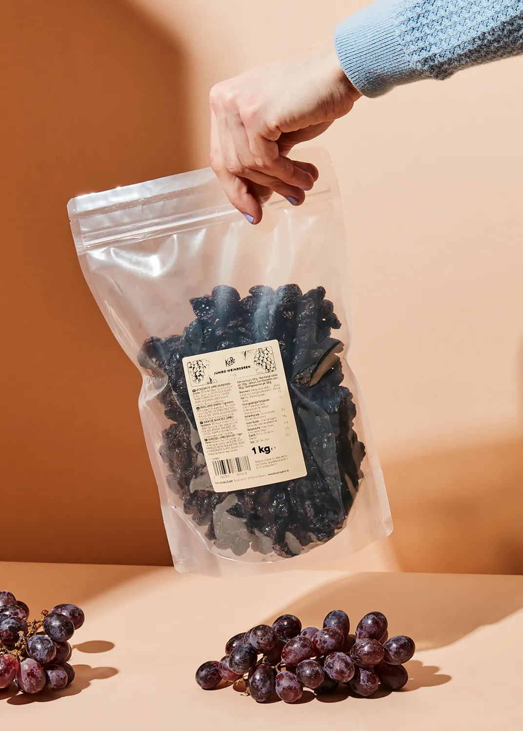 a person is holding a bag of grapes that says 1 kg on it