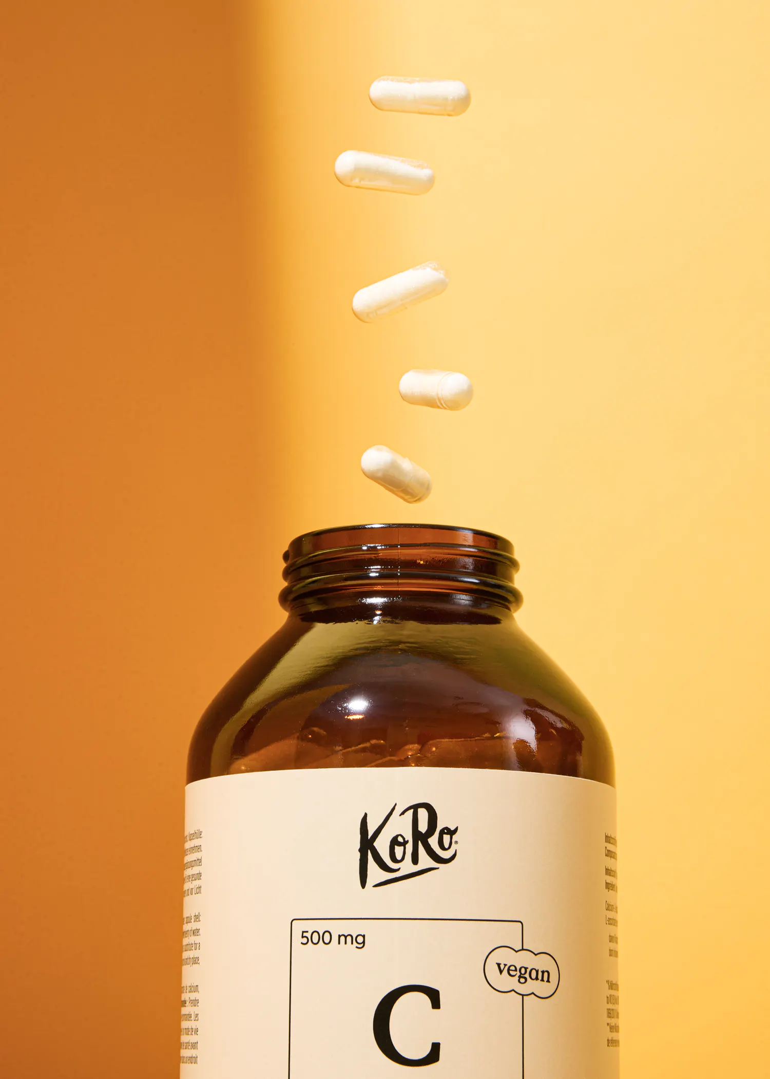 a bottle of koro vegan vitamin c with capsules falling out of it