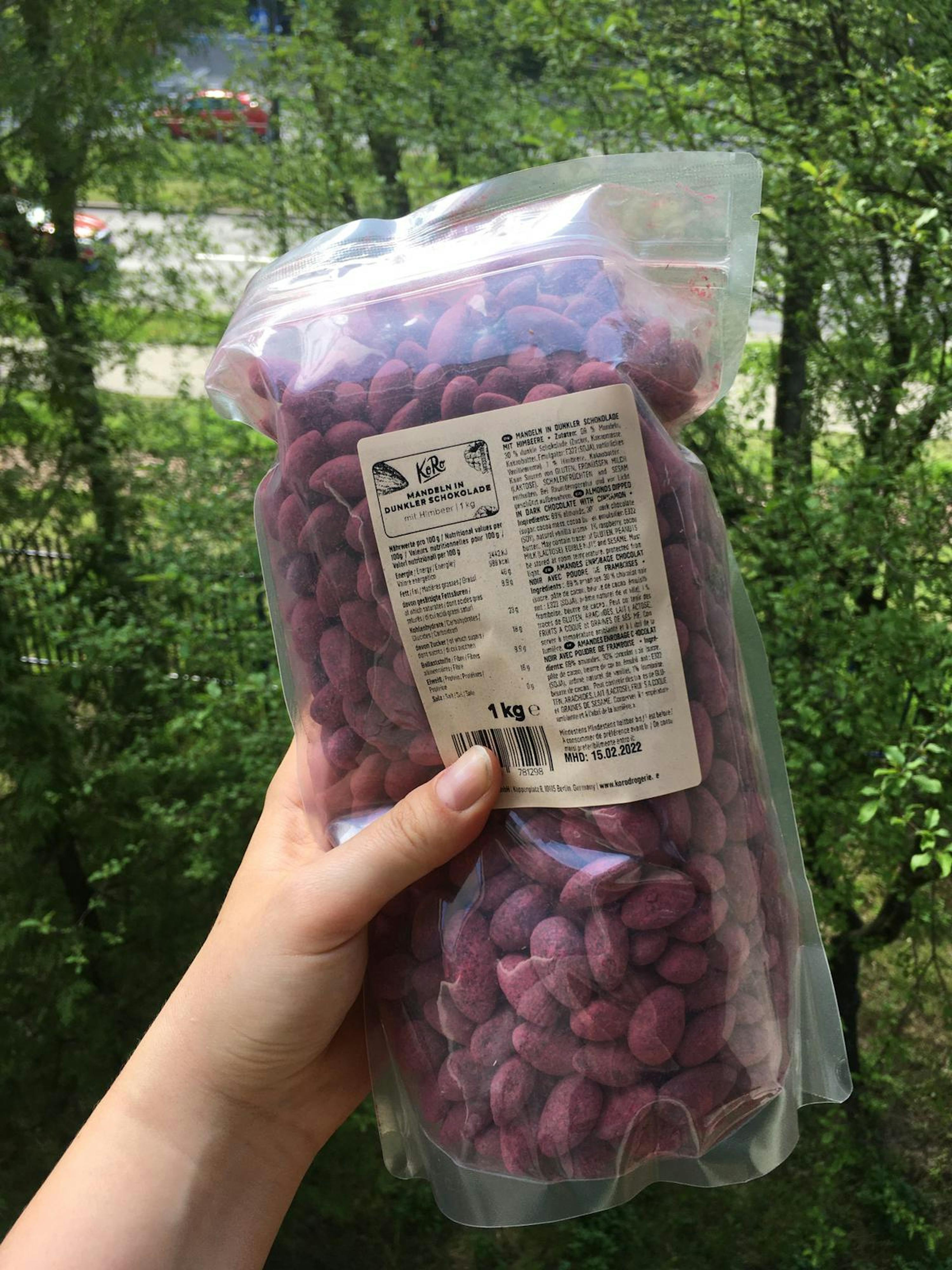 eine Person hält einen Plastikbeutel mit lila Erdnüssen in der Hand