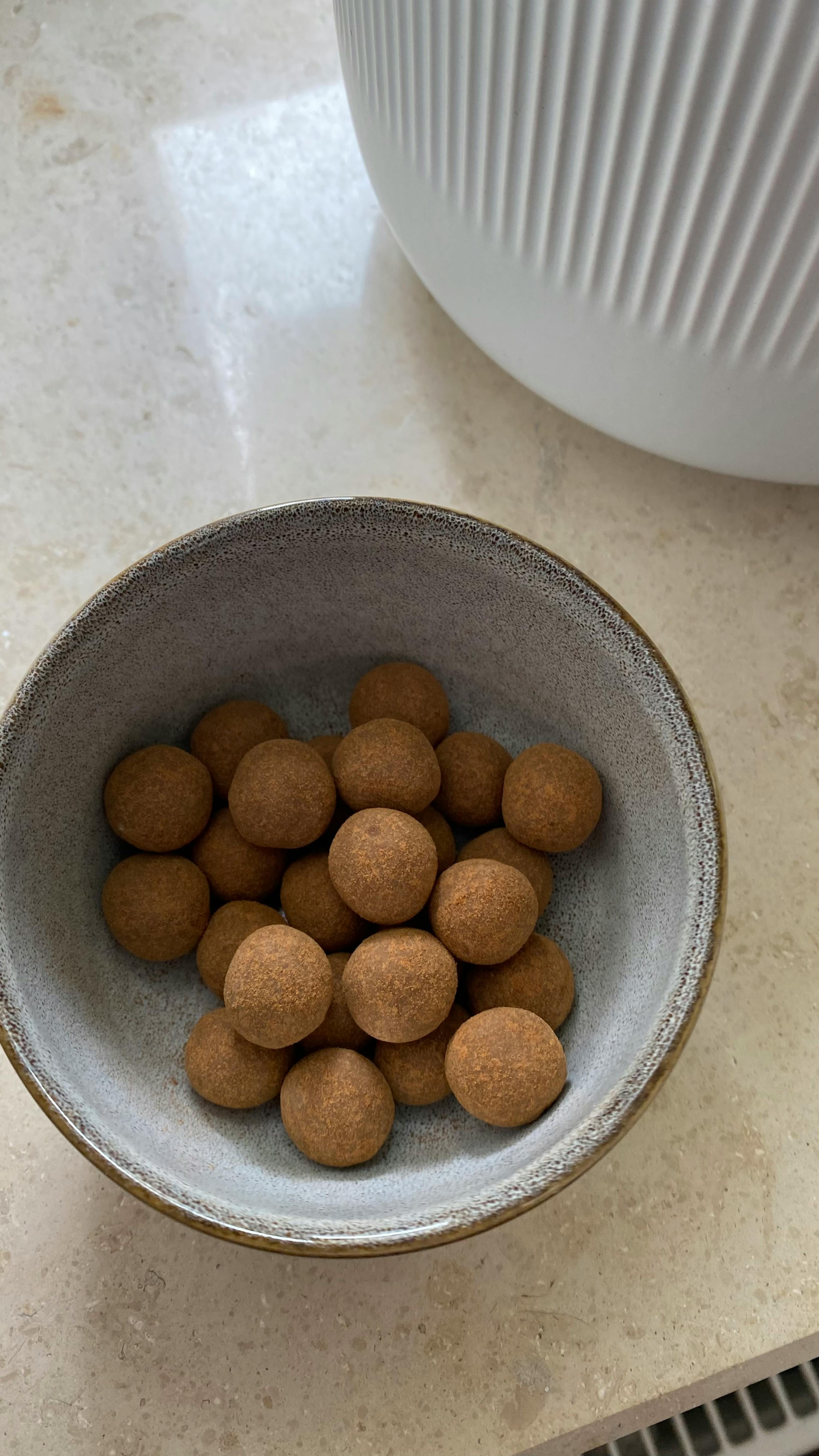 eine kleine graue Schüssel mit braunen Erdnüssen auf einem Tisch