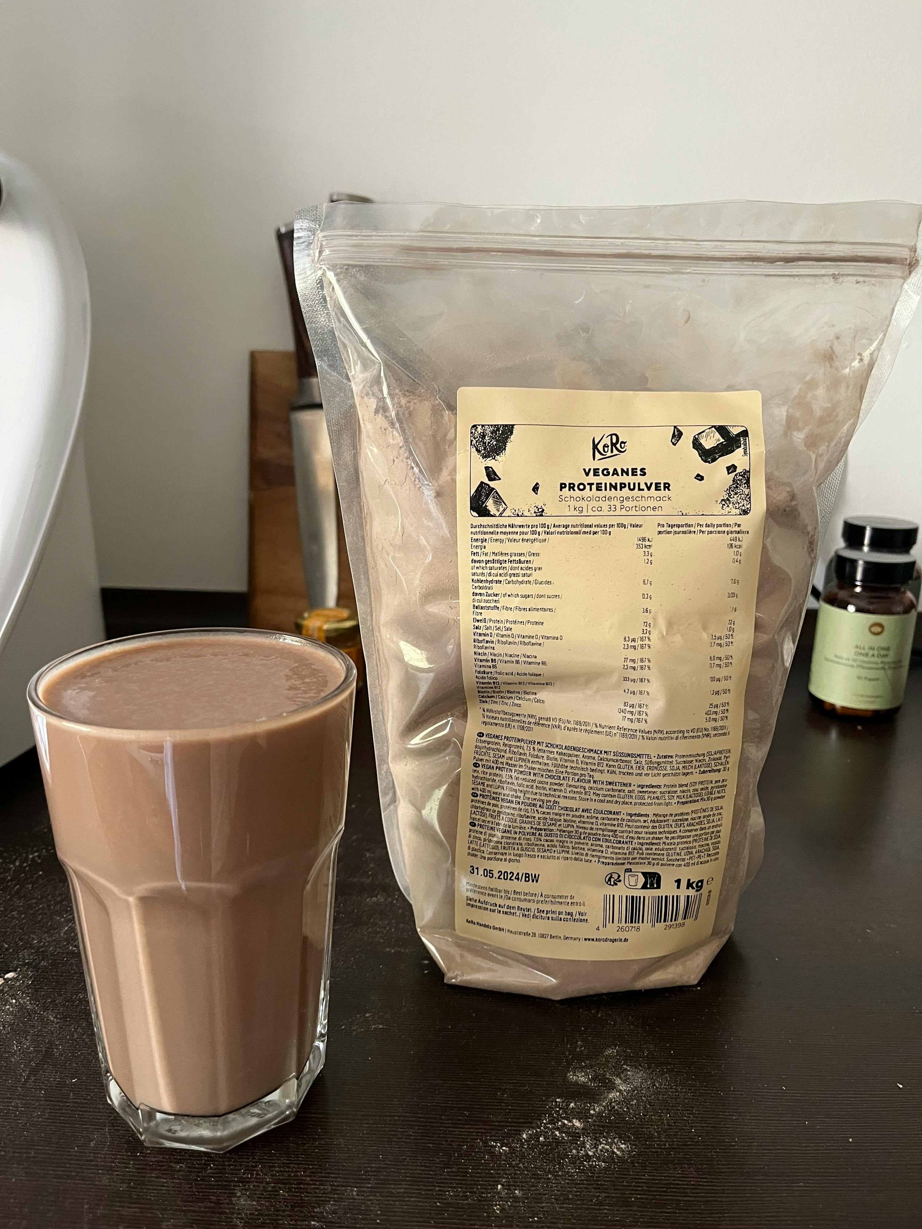 a bag of protein powder sits next to a glass