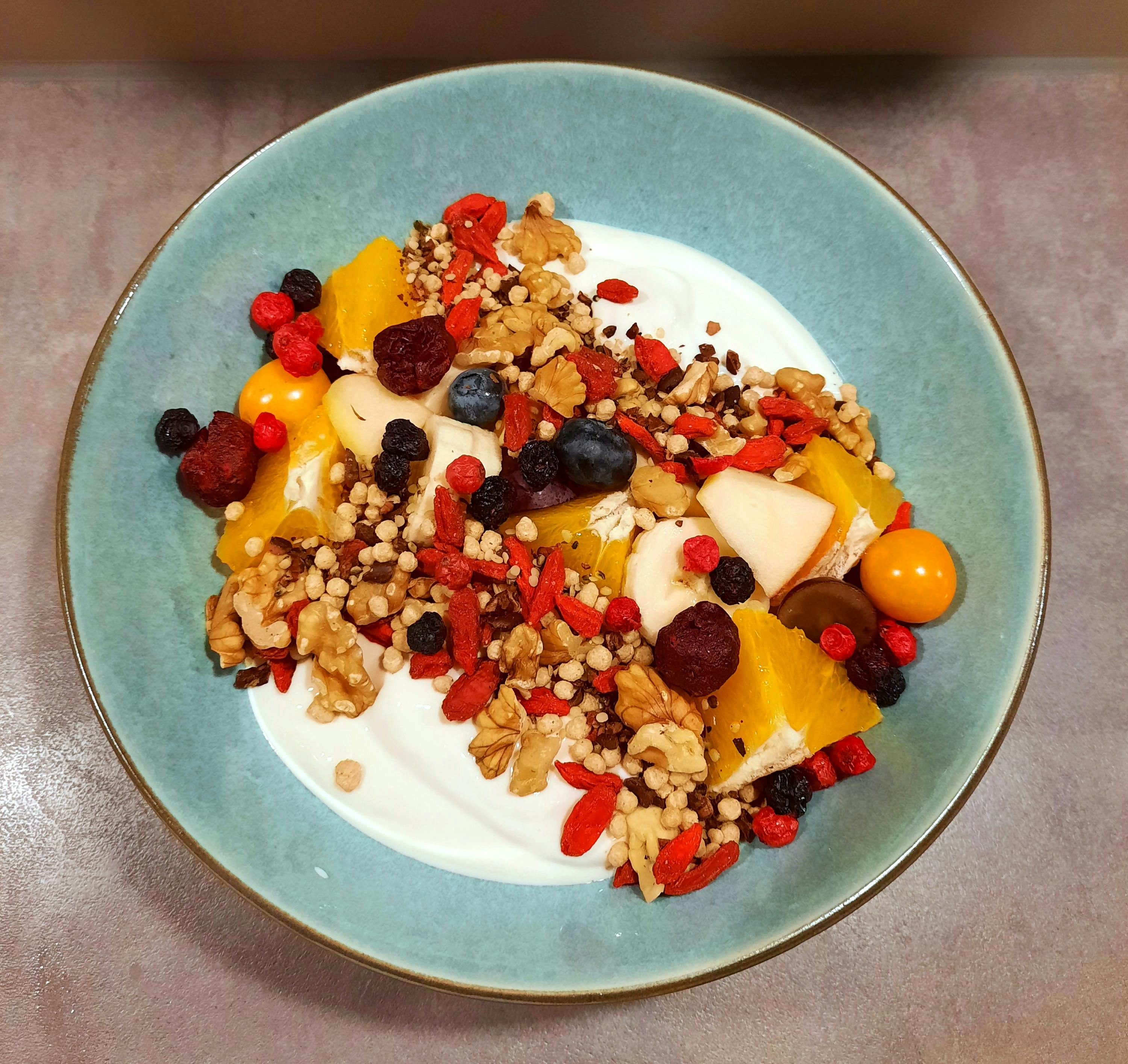 a blue bowl filled with yogurt nuts and fruit