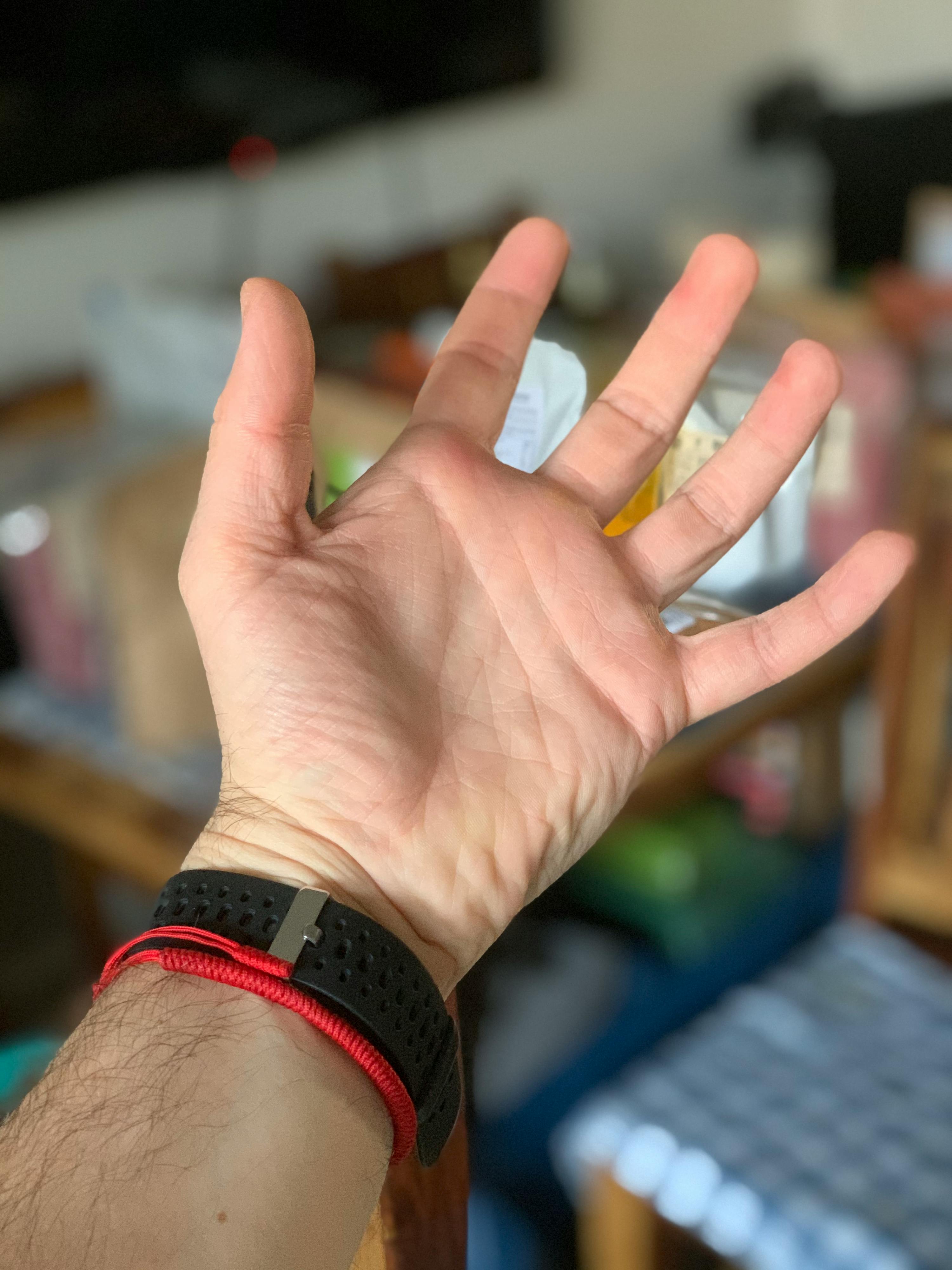a man 's hand with a red bracelet on it