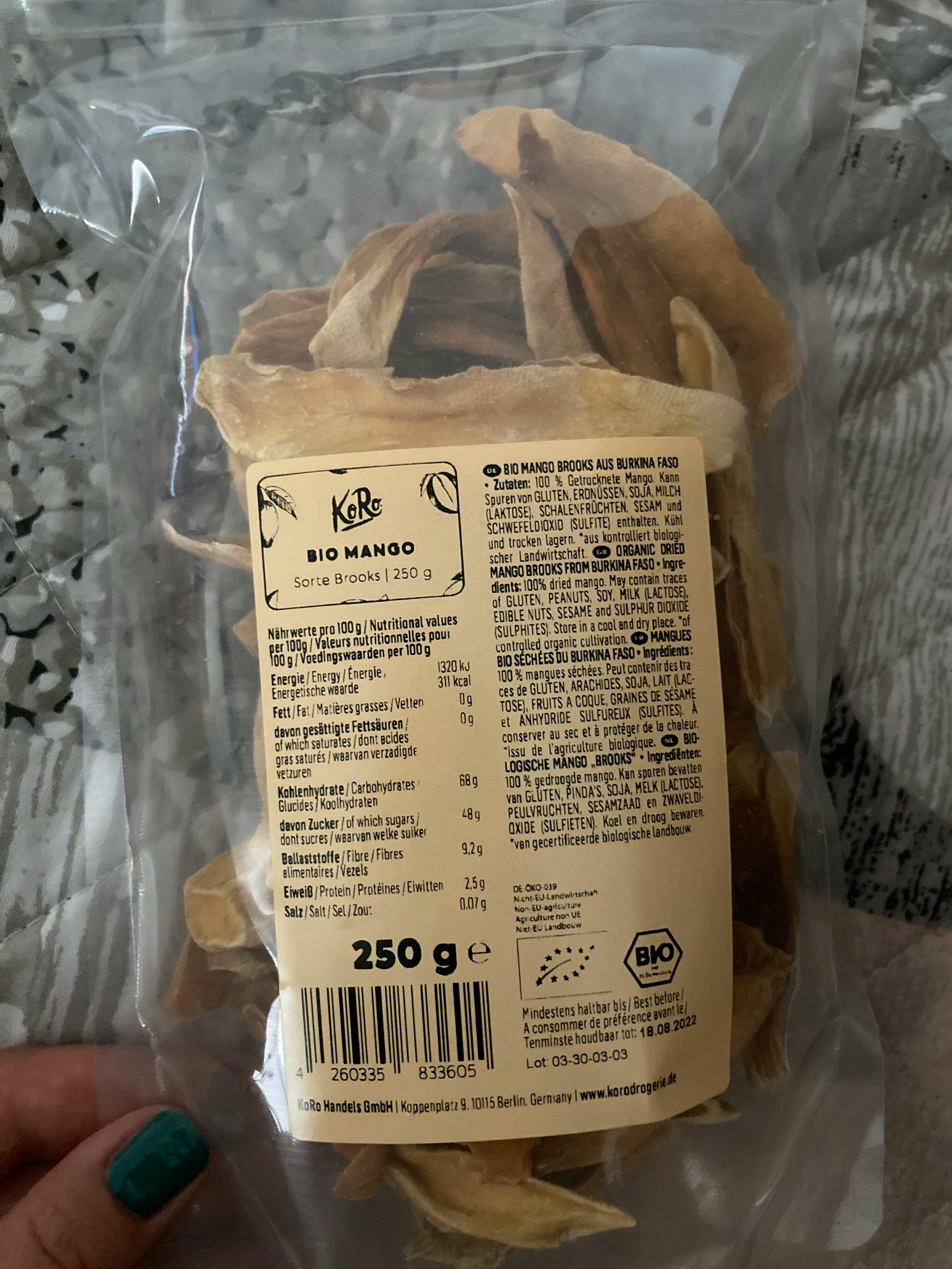 una persona tiene in mano un sacchetto di mango essiccato bio