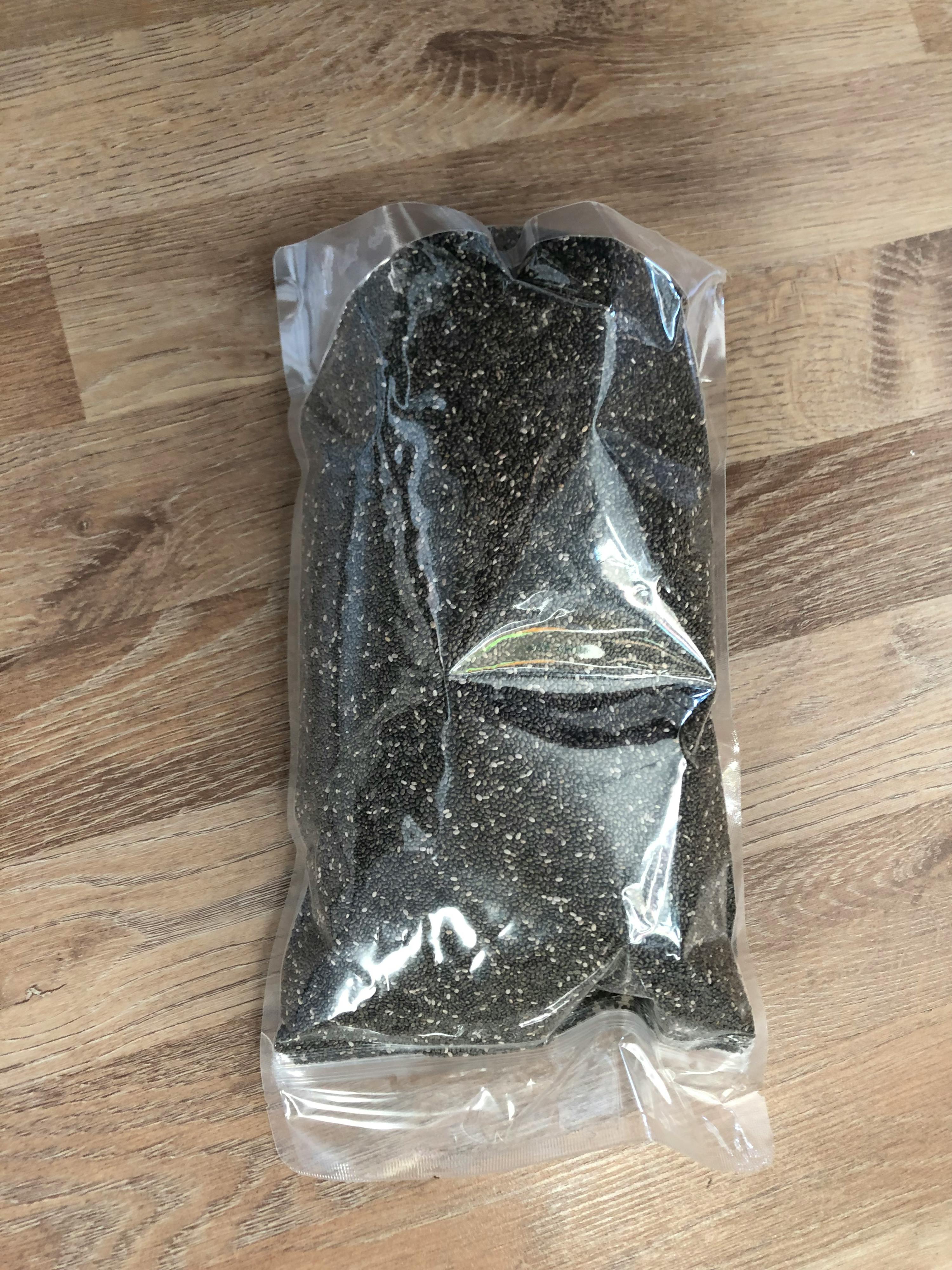 eine Plastiktüte mit schwarzen Samen liegt auf einem Holztisch