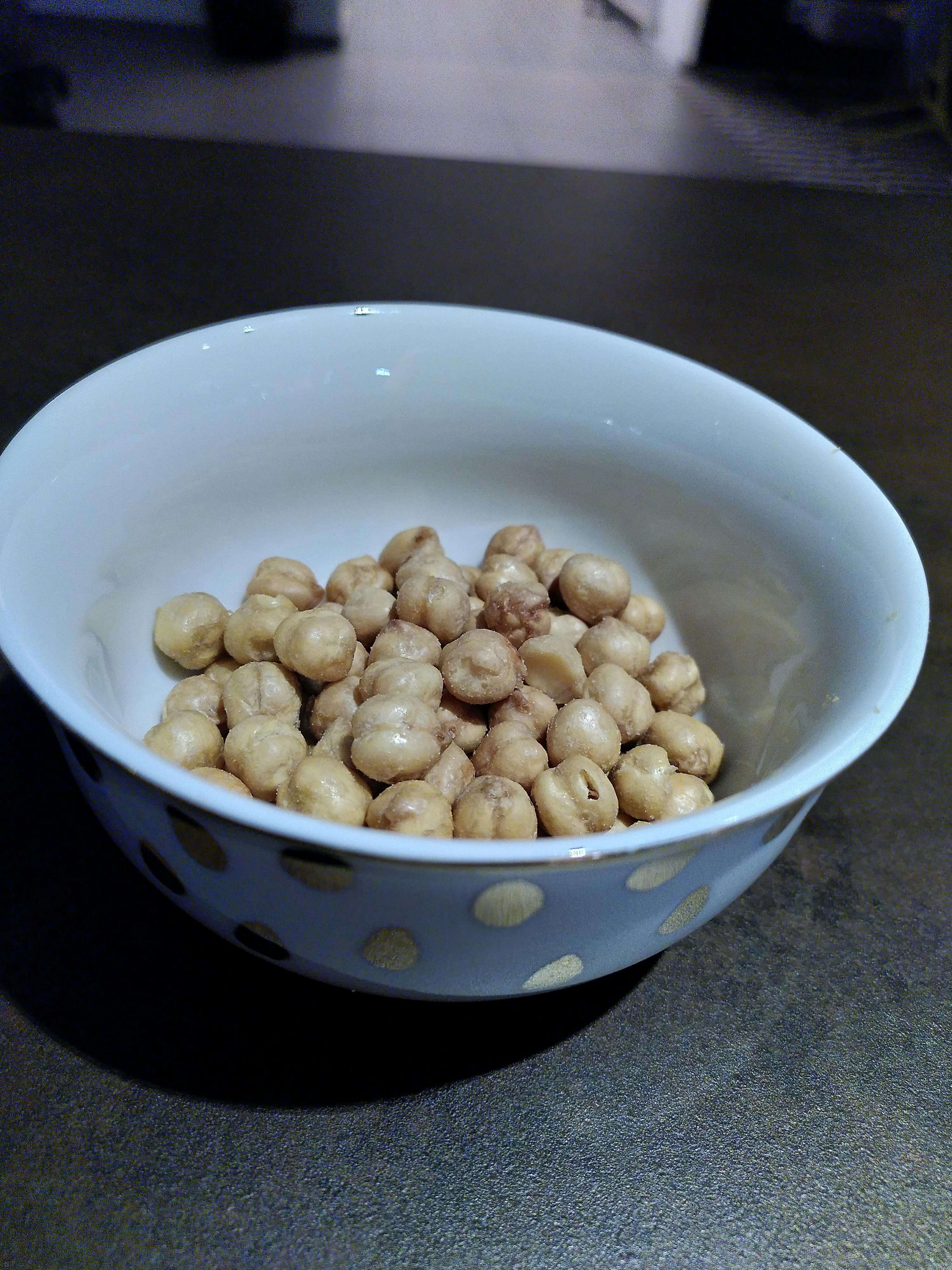 una ciotola bianca e oro piena di ceci su un tavolo