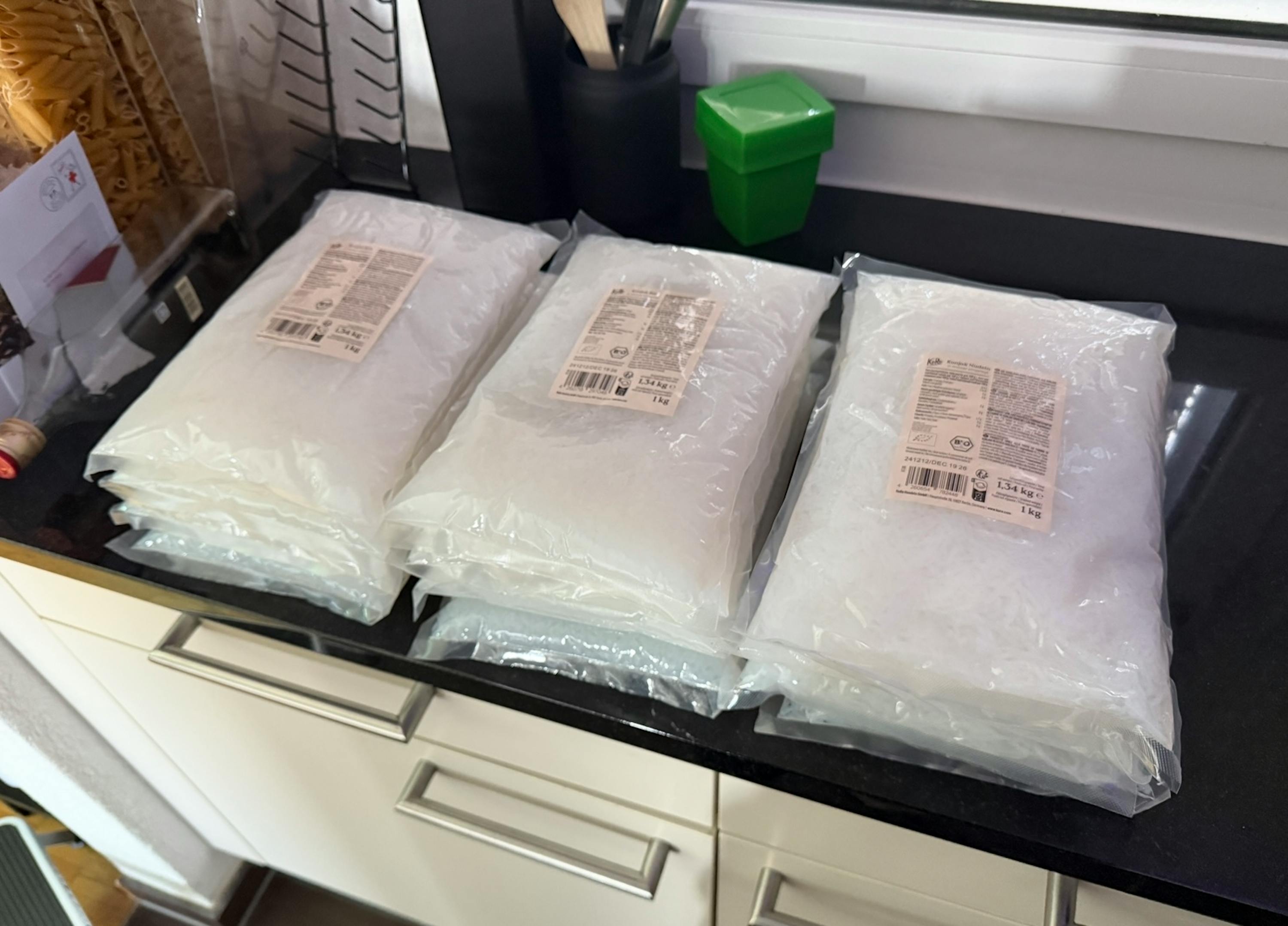 three bags of white powder are sitting on a kitchen counter