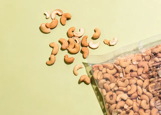 eine Tüte Cashewnüsse liegt auf einem Tisch neben einem Haufen Cashewnüsse