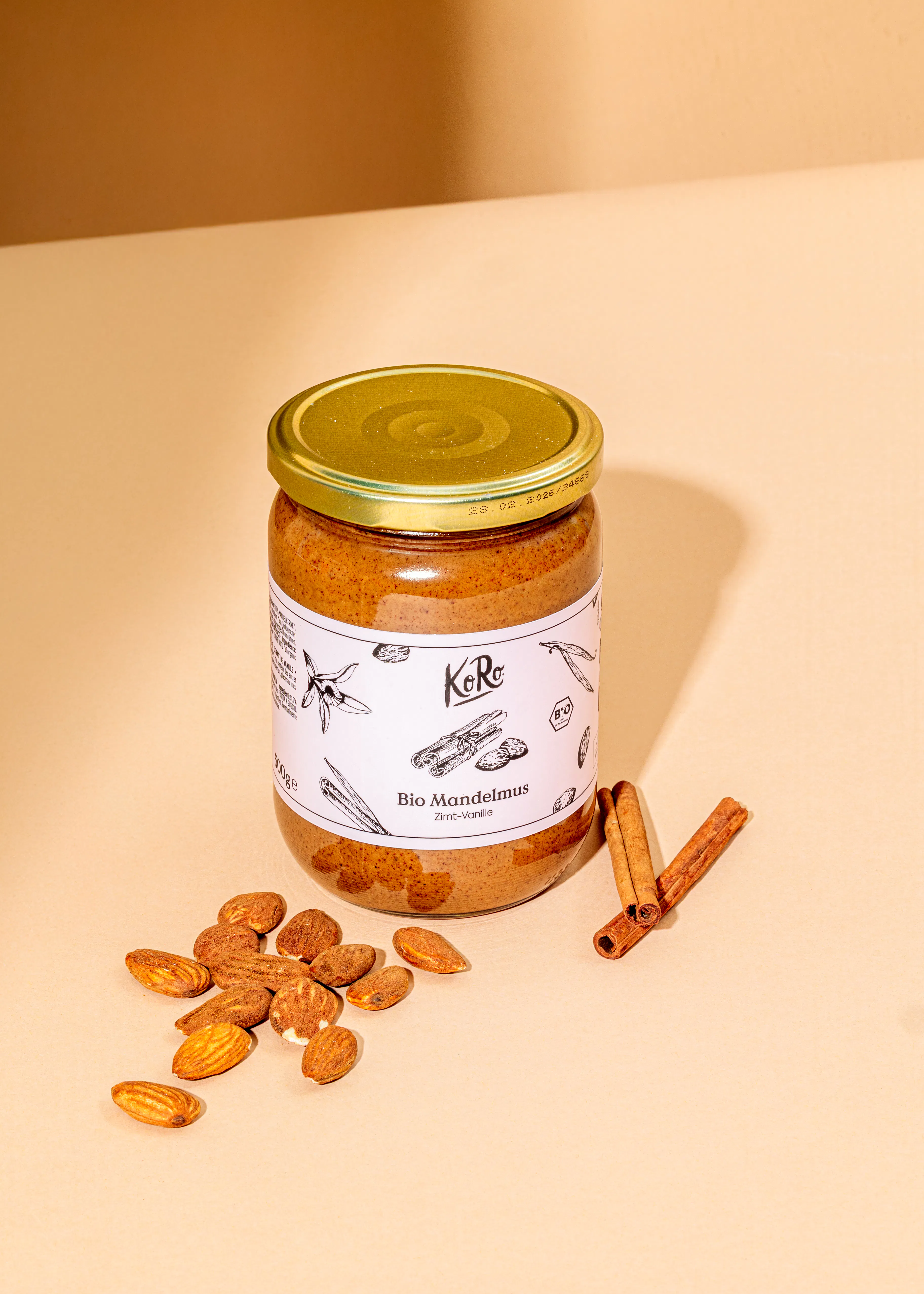 ein Glas Bio-Mandelmus steht neben einem Haufen Mandeln