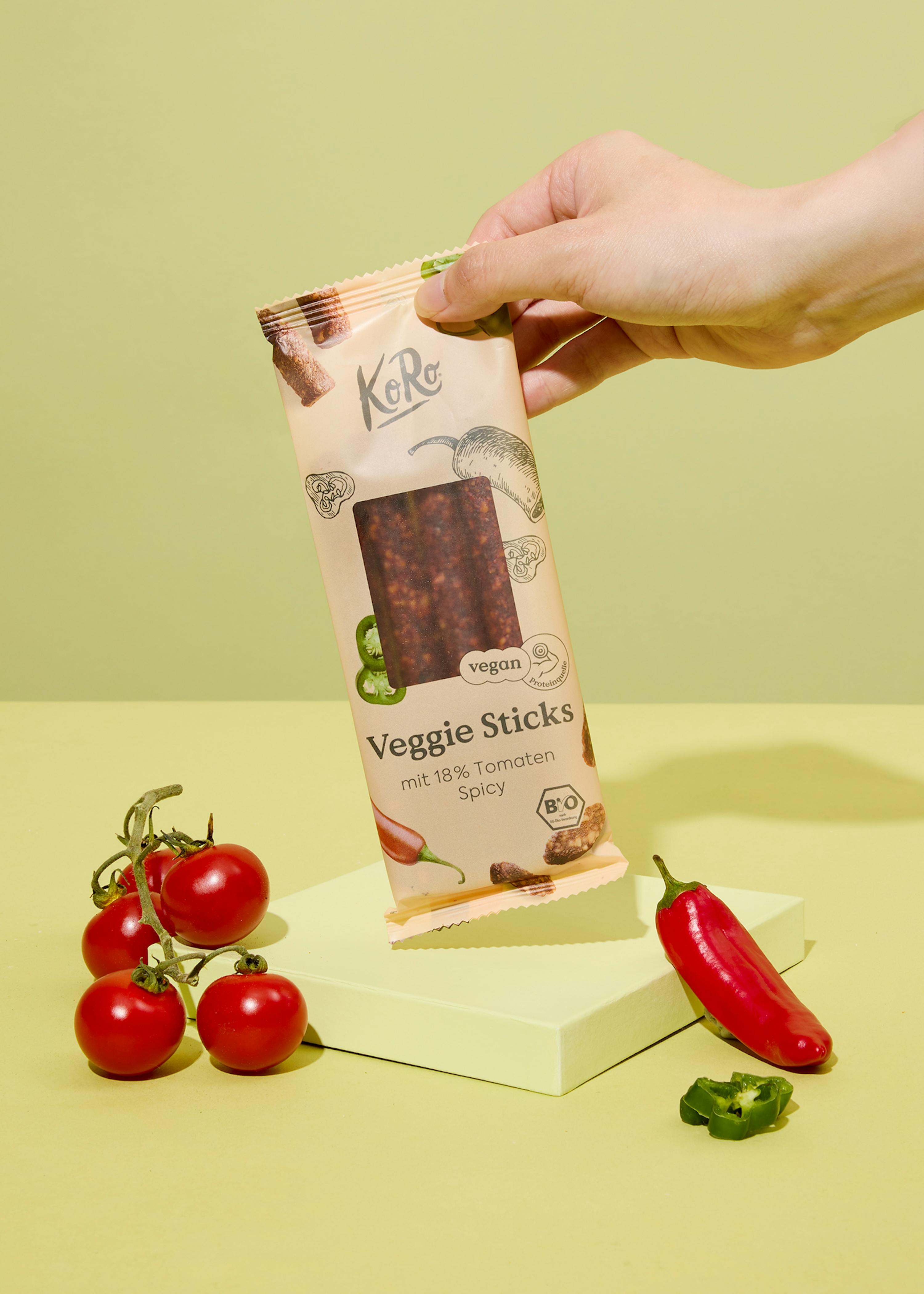 une personne tient une boîte de bâtonnets de légumes épicés