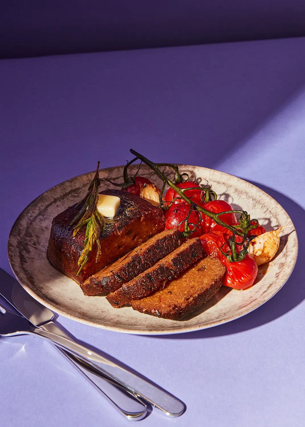 ein Teller mit einem Stück Fleisch und Tomaten darauf