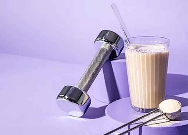 ein Glas Milchshake mit einem Strohhalm neben zwei Hanteln .