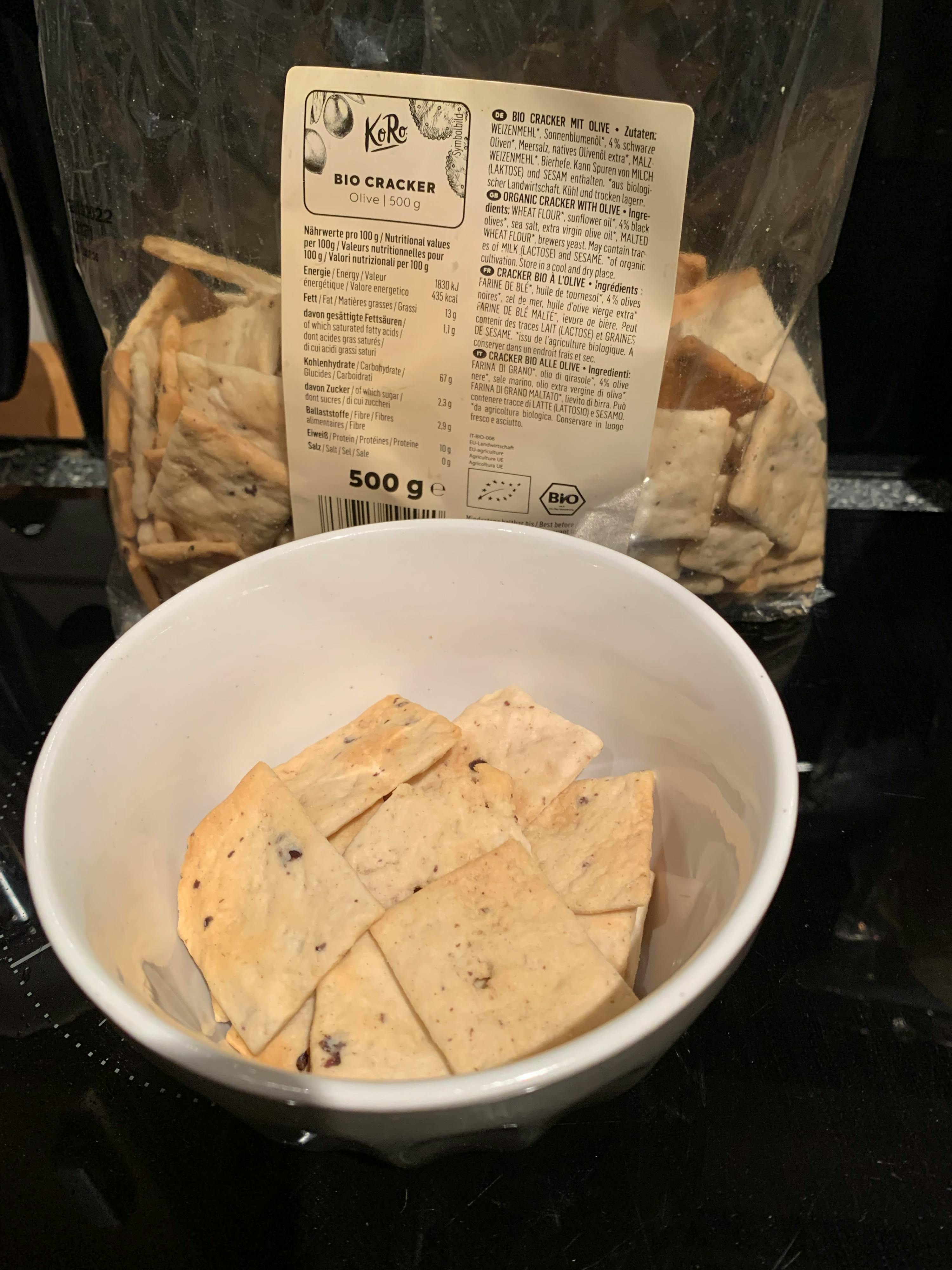 una ciotola piena di cracker è accanto a un sacchetto di cracker