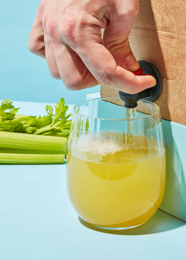 una persona vierte un líquido amarillo en un vaso