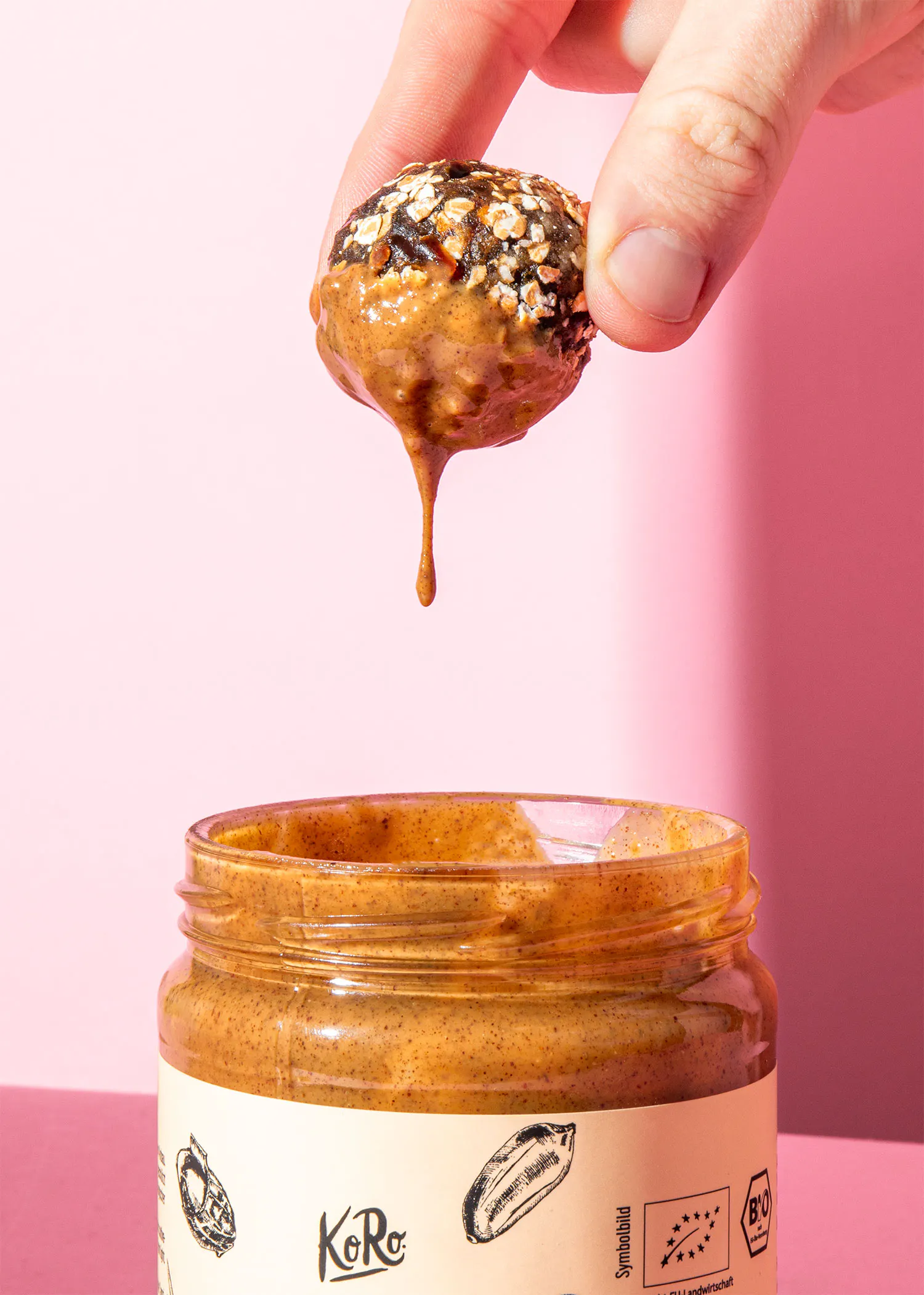 une main tient une balle remplie de beurre de cacahuète à côté d' un pot de beurre de cacahuète