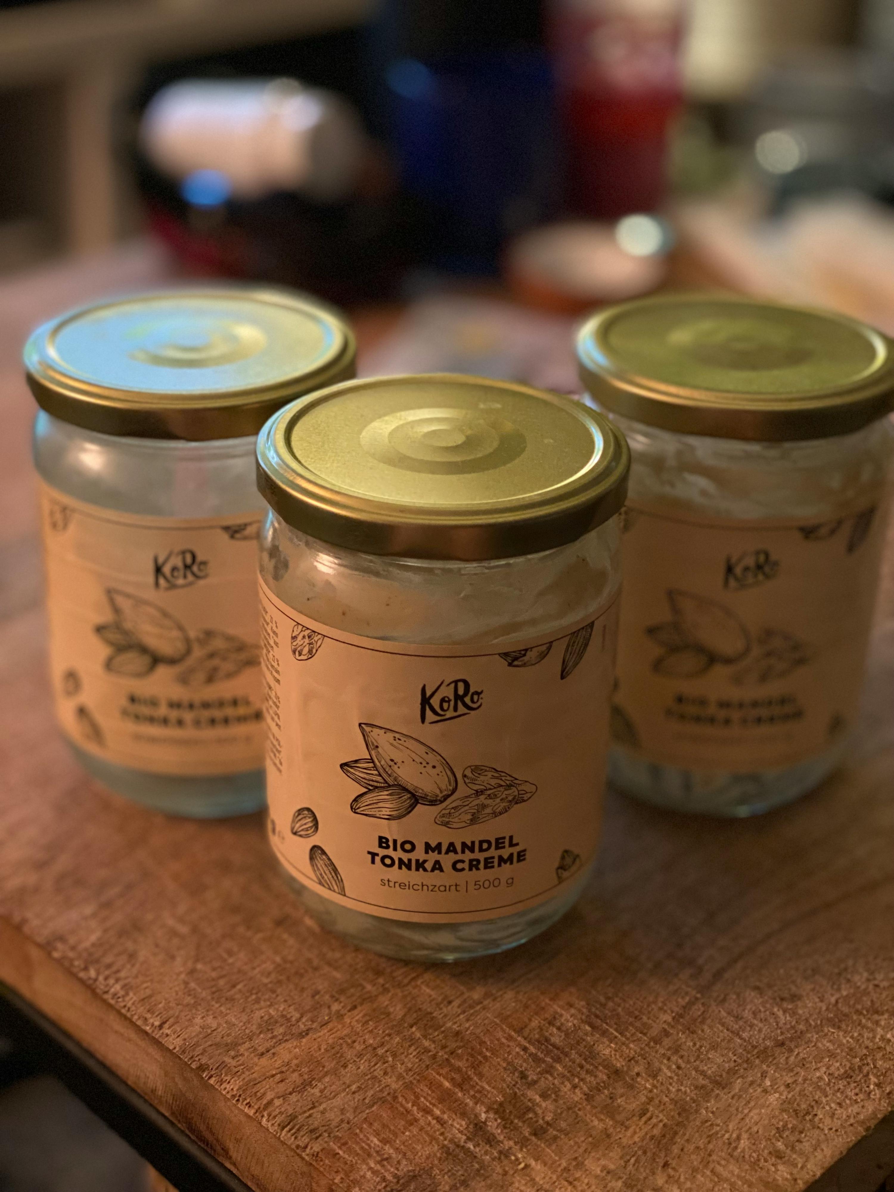 drei Gläser bio mandel tonka creme stehen auf einem Holztisch