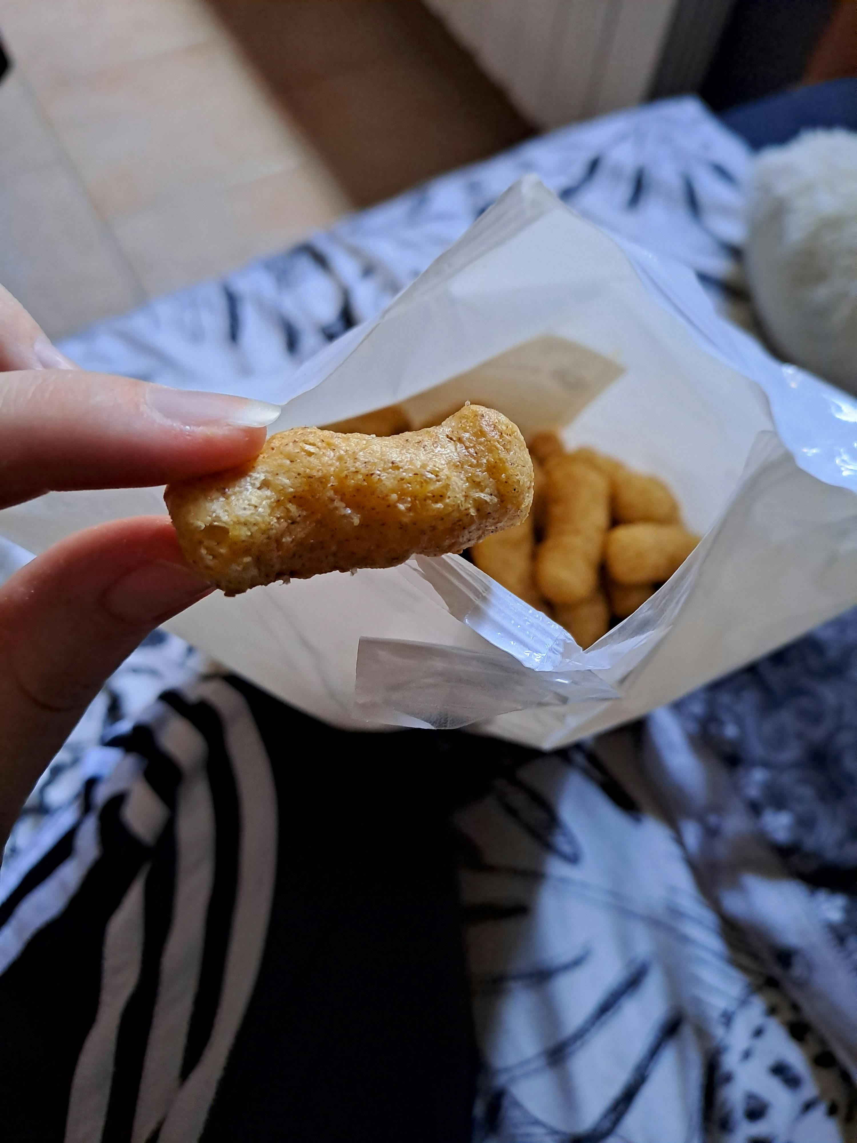 a person is holding a piece of fried food in their hand
