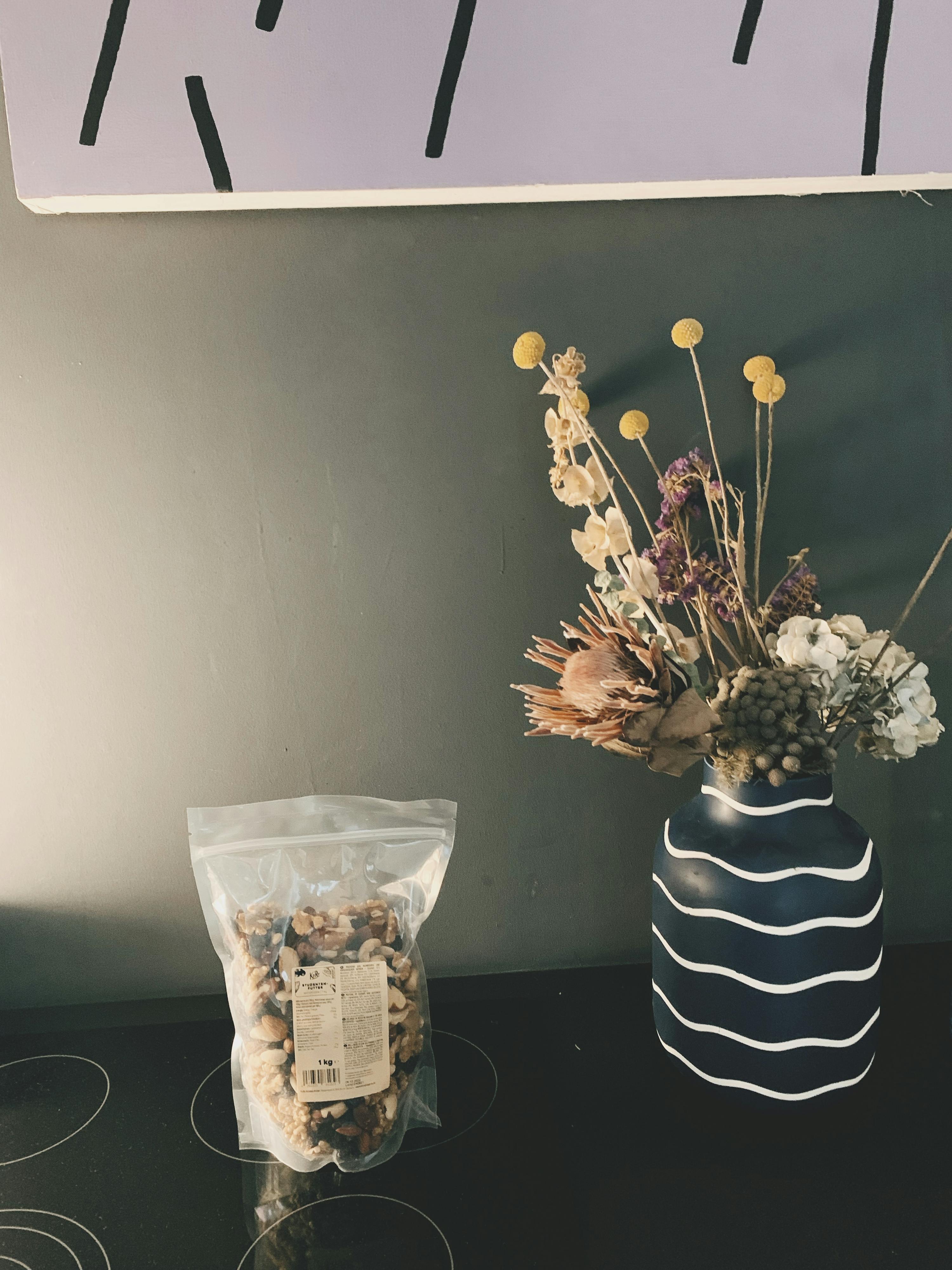 un sacchetto di noci è seduto accanto a un vaso di fiori secchi