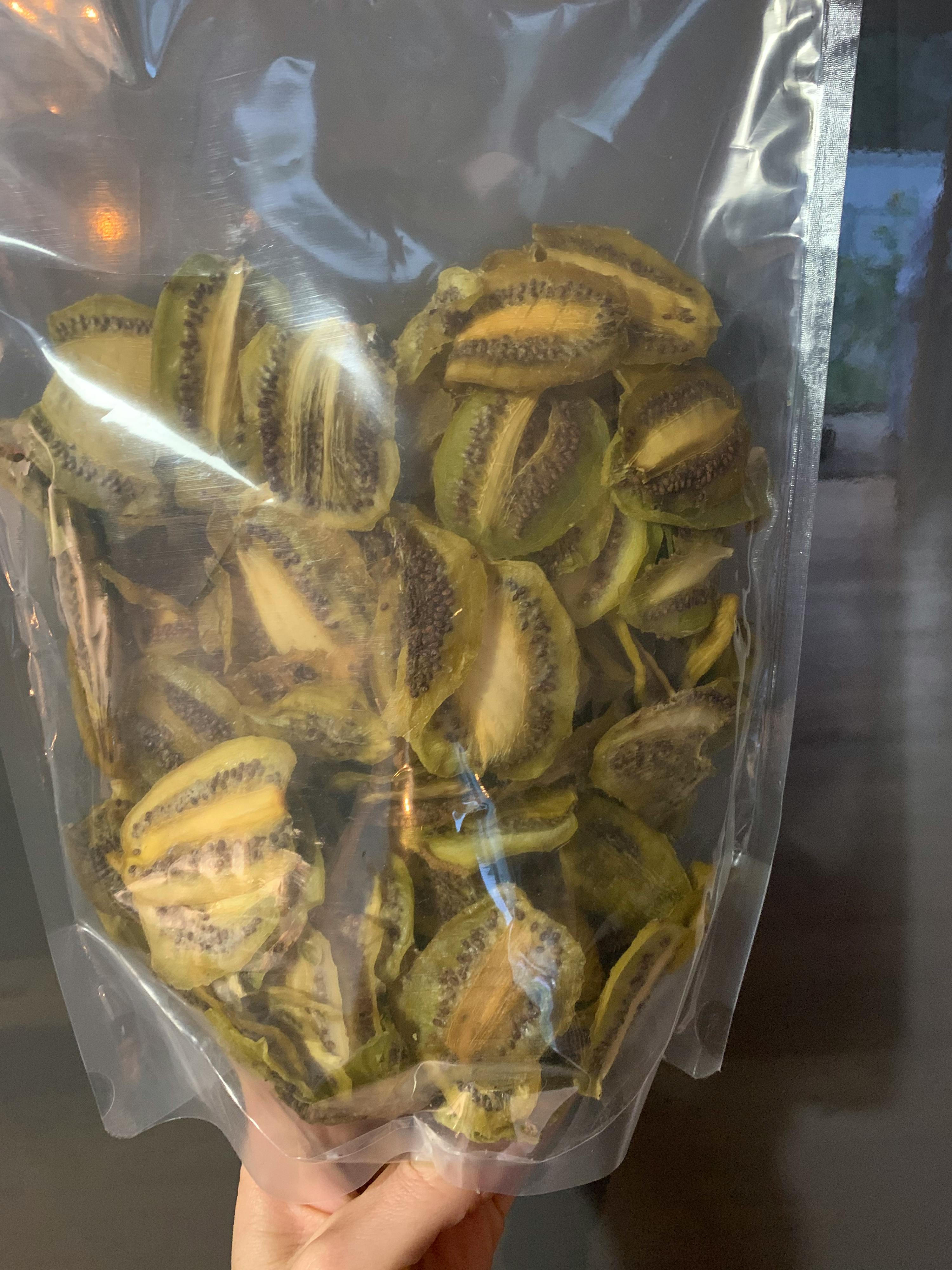 eine Person hält einen Plastikbeutel mit getrockneten Kiwis darin