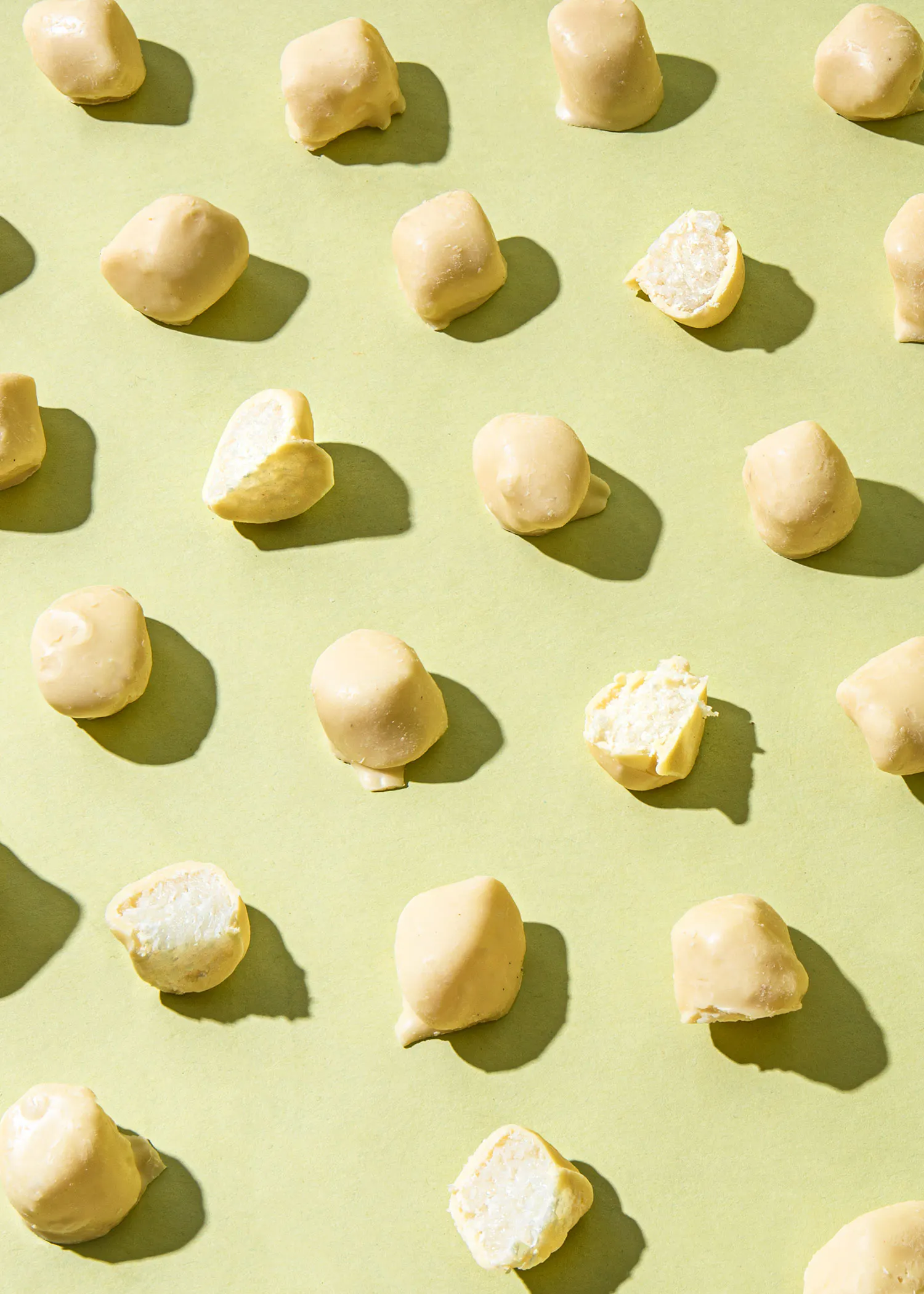 eine Reihe weißer Schokoladenbonbons auf einem grünen Hintergrund