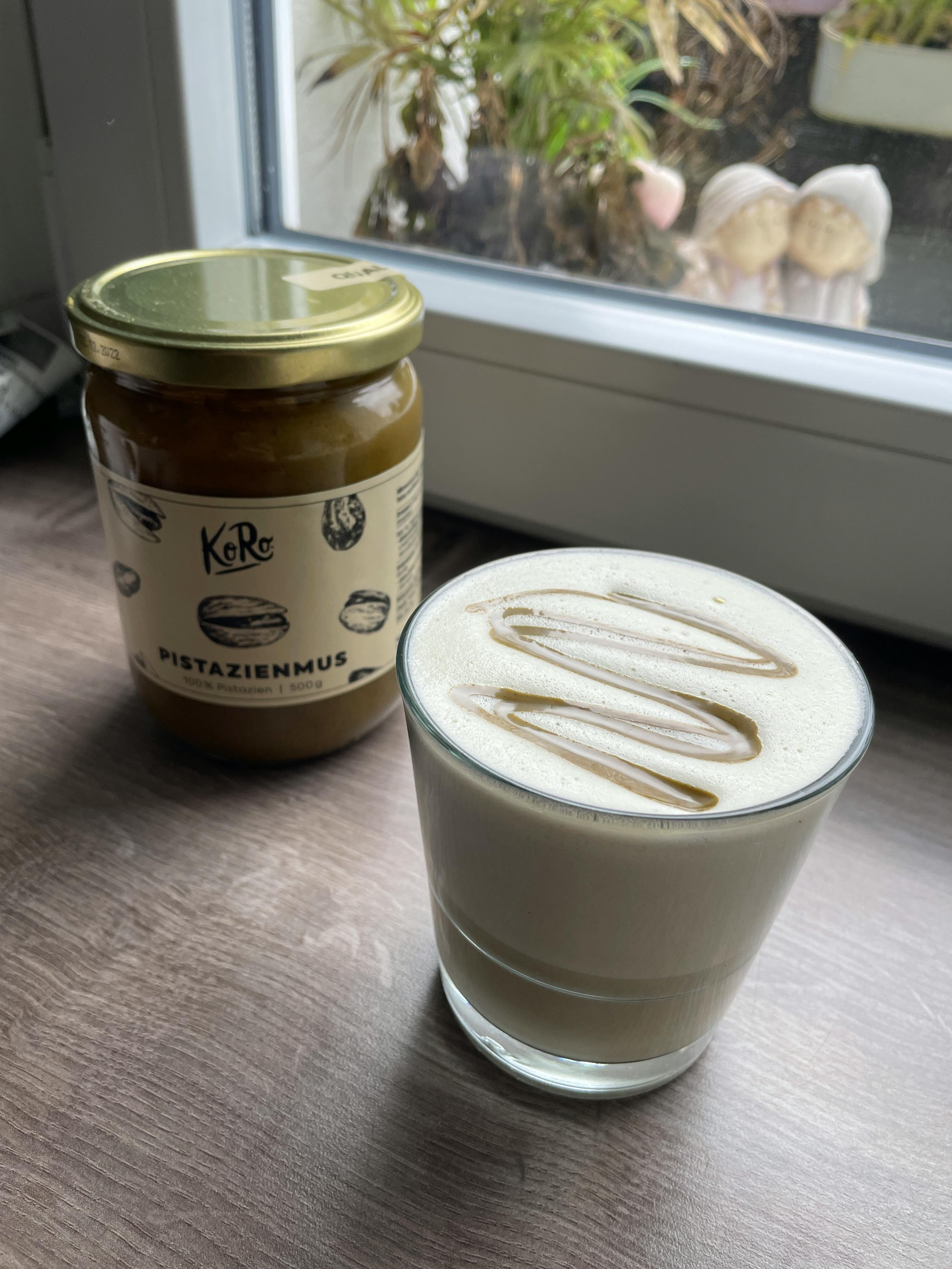 a jar of pistazienmus sits next to a glass of milk