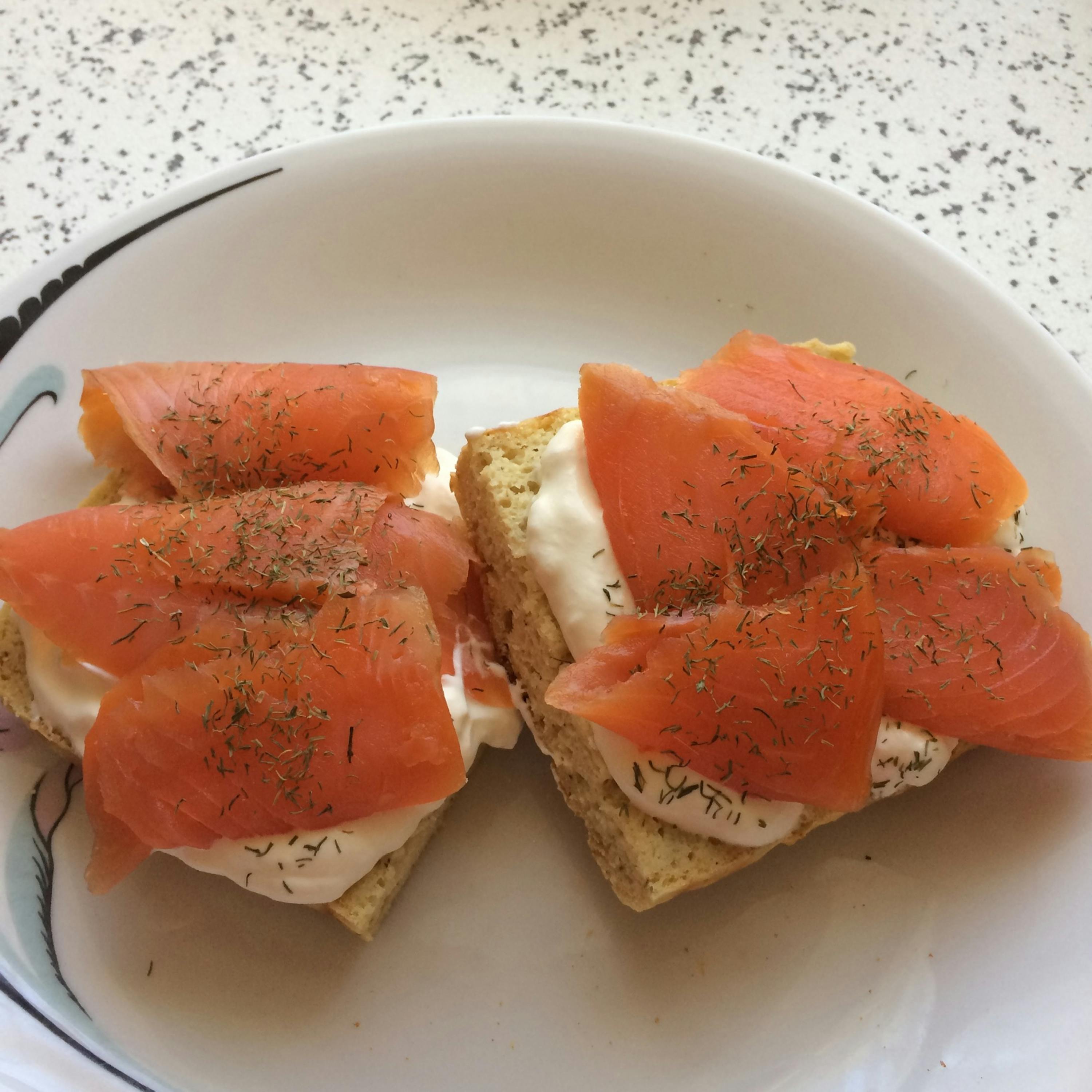 two slices of smoked salmon on toast with sour cream and dill on a plate