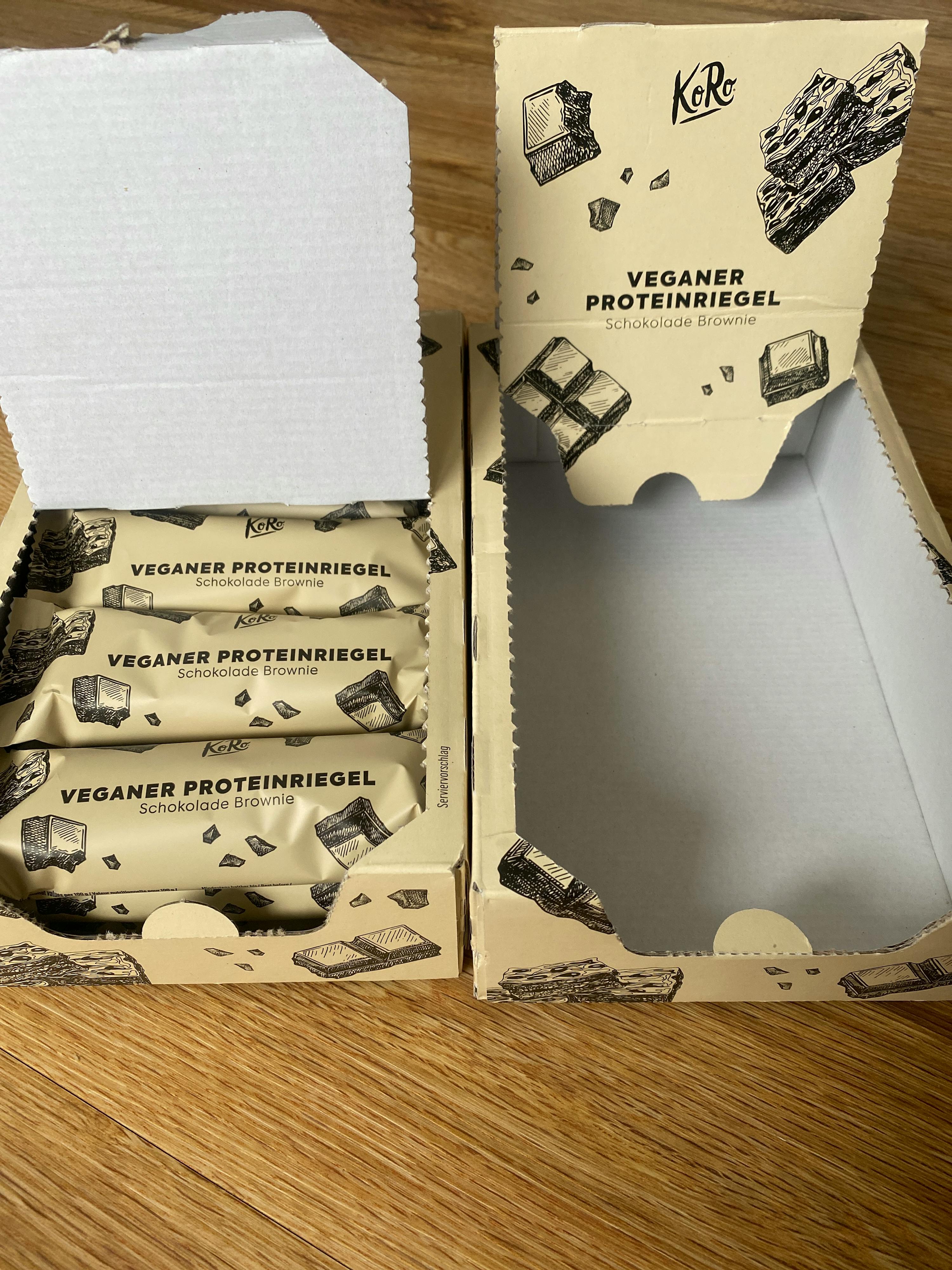 a box of veganer proteinriegel sits on a wooden floor