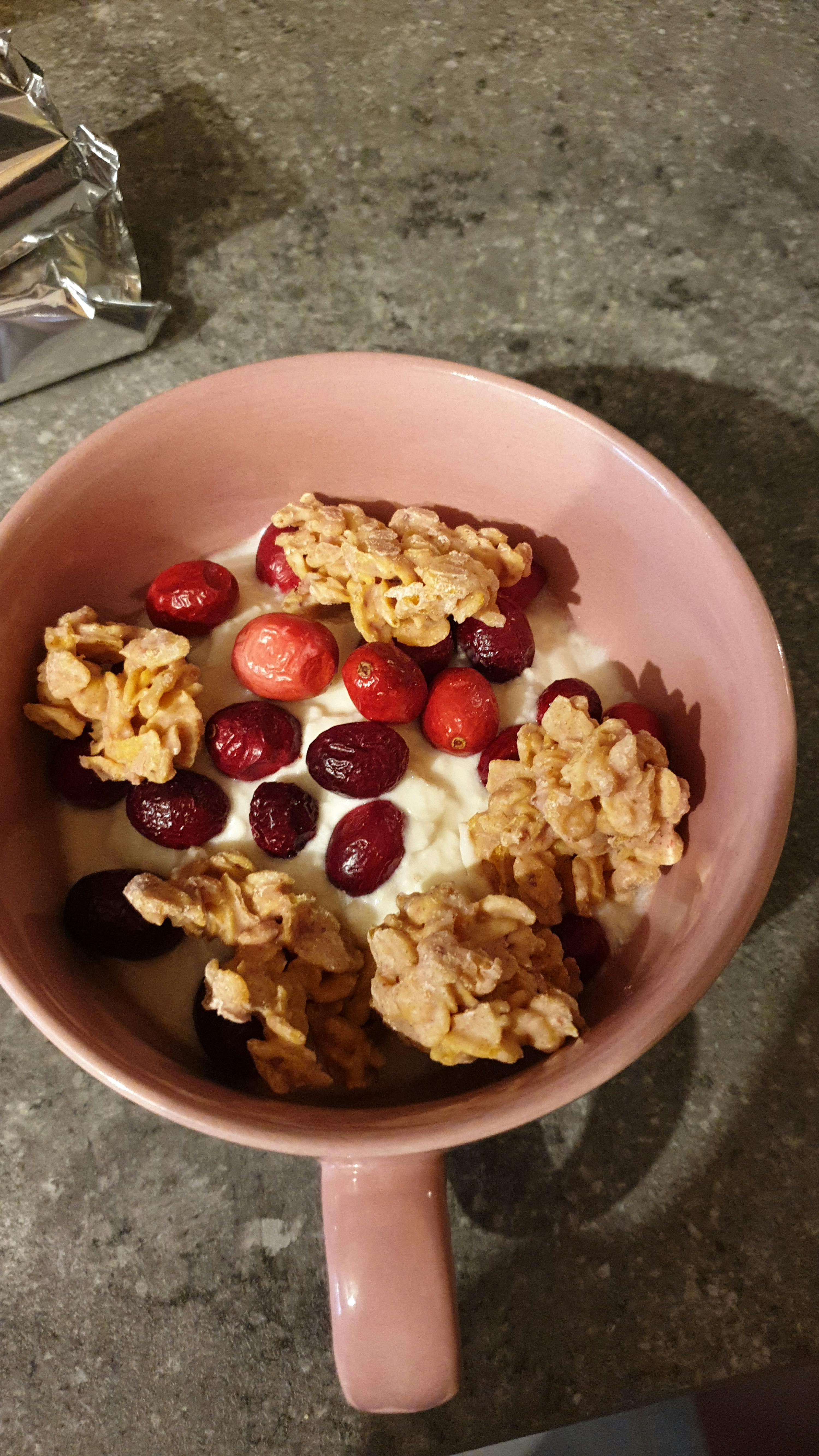 a pink bowl filled with yogurt cranberries and granola
