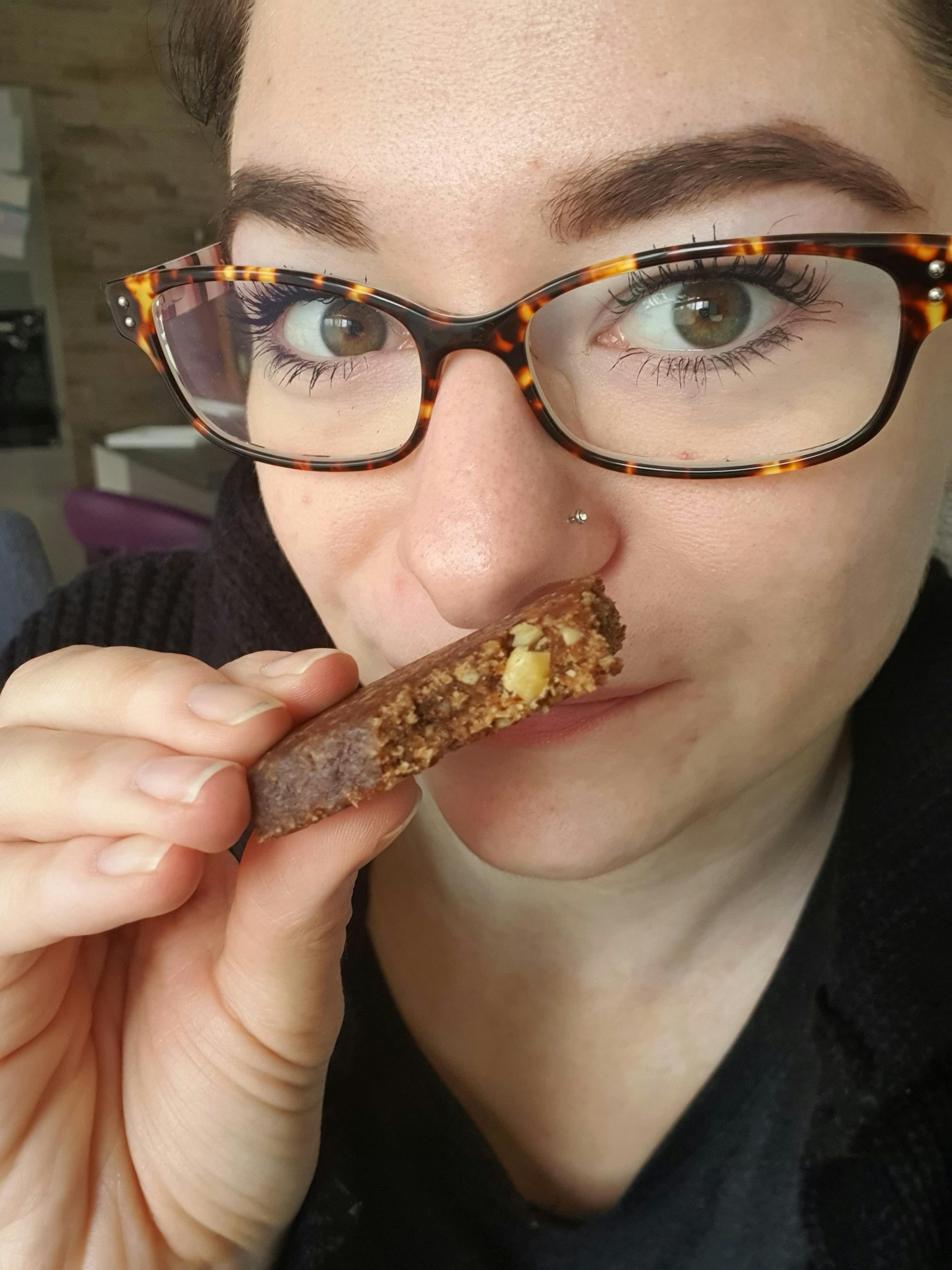 a woman wearing glasses is holding a piece of food in her hand