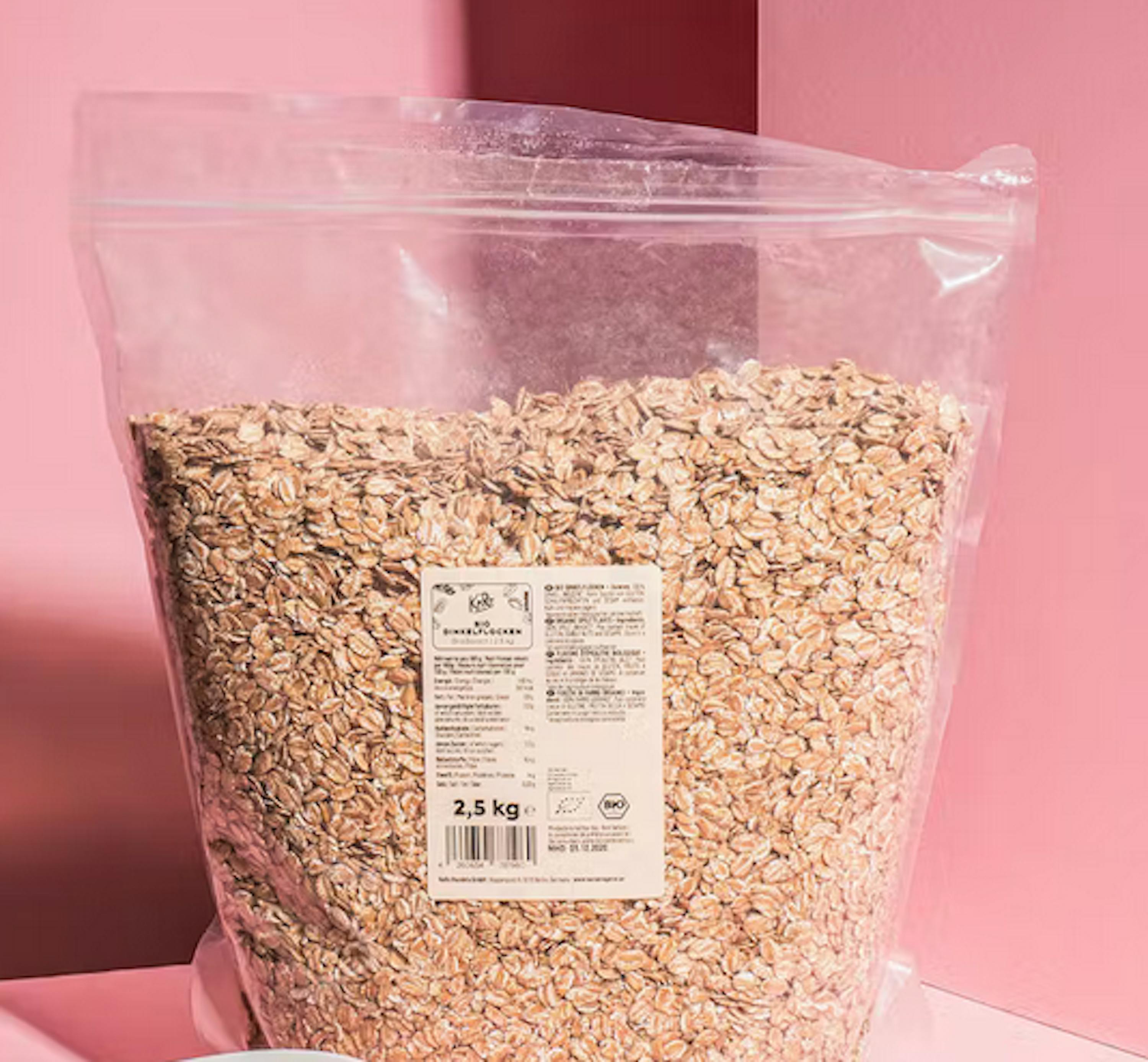 eine Plastiktüte mit Haferflocken steht auf einem rosa Tisch
