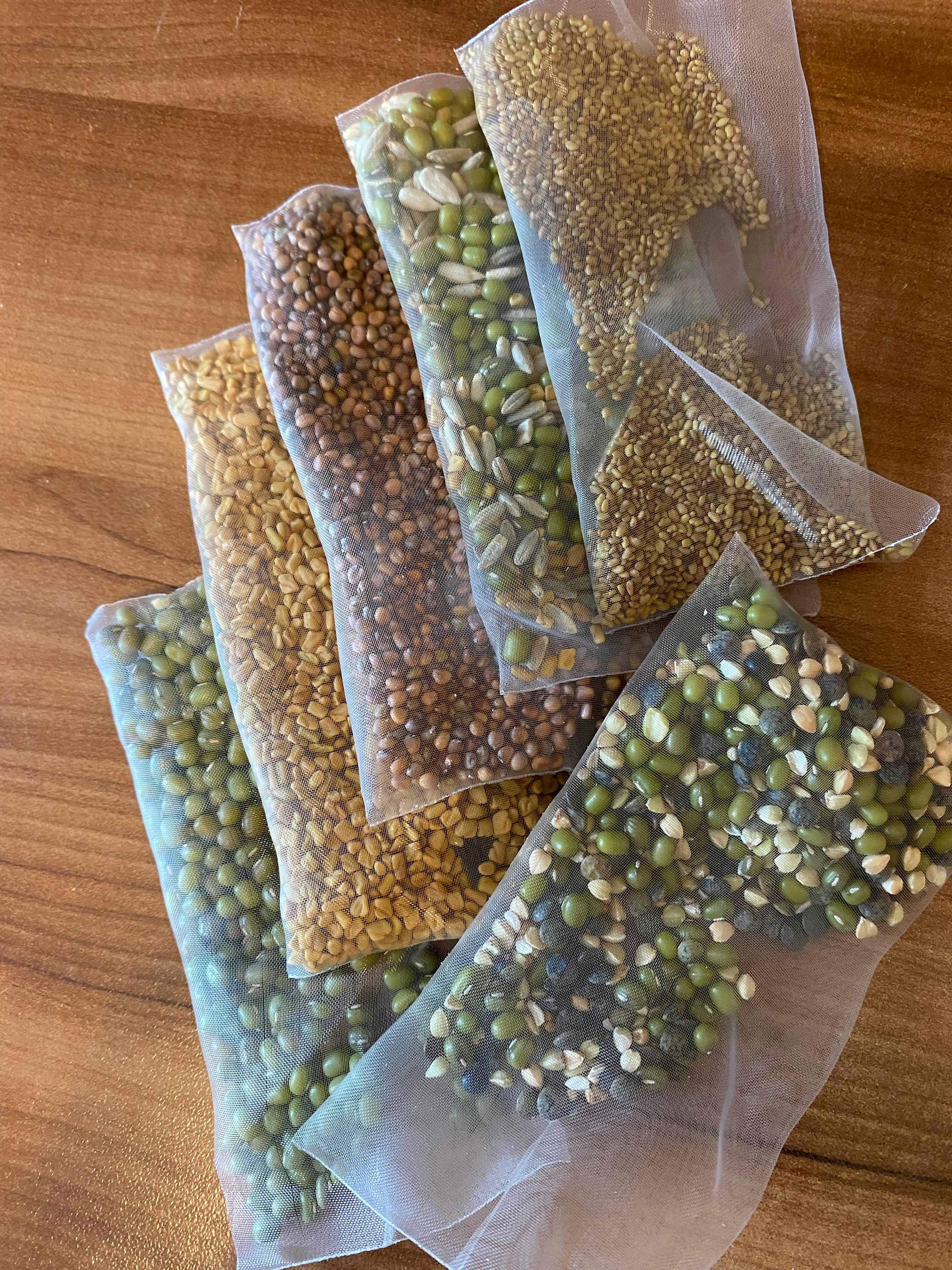 a variety of seeds and grains in bags on a wooden table